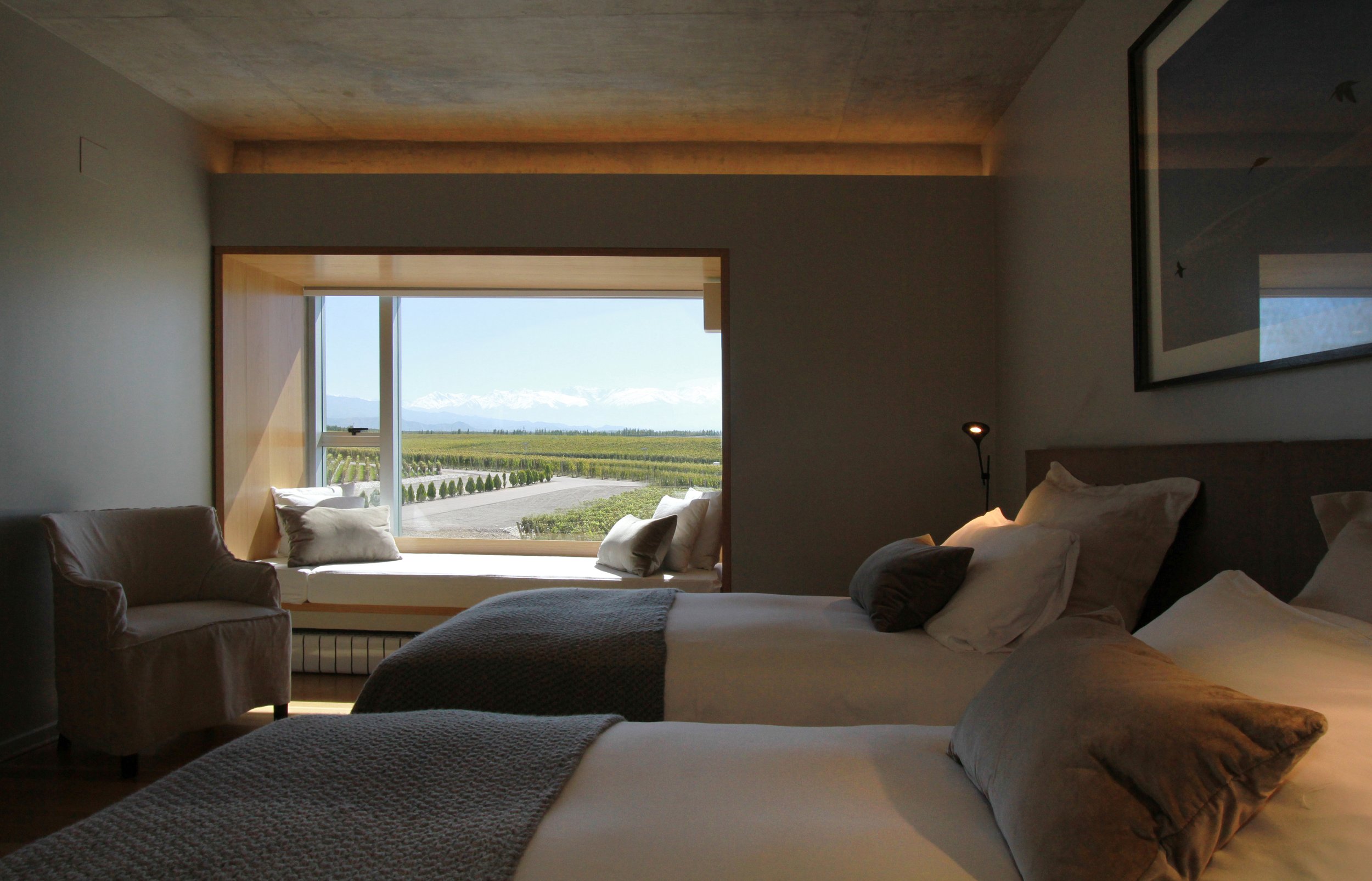 Habitación de hotel con dos camas y un gran ventanal con vistas a los viñedos.
