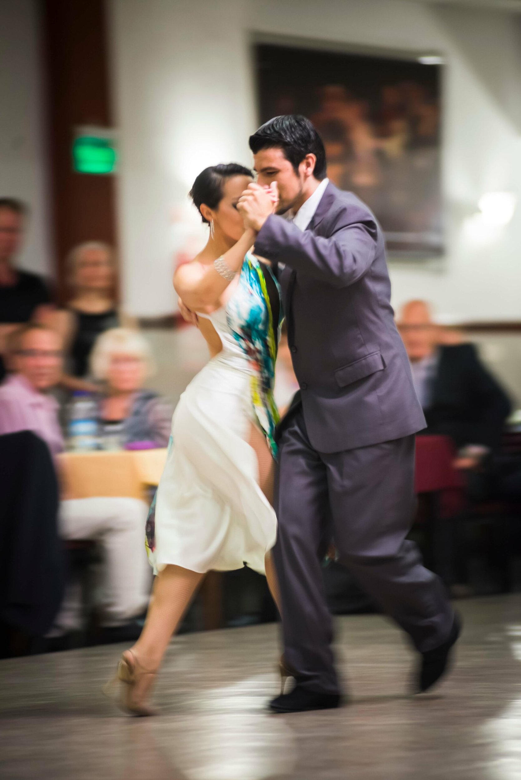 Pareja bailando tango en un escenario de salón frente al público en Buenos Aires.
