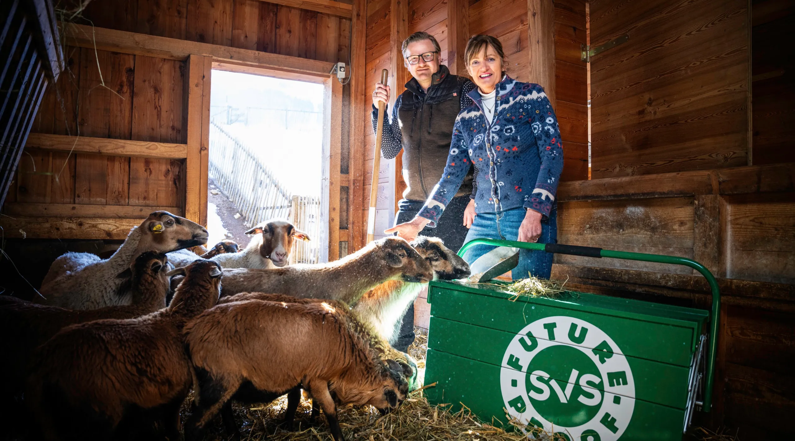 SVS FUTUREPROOF: Bäuerin und Bauer im Stall mit Schafen und der grünen SVS-Werkzeugkiste