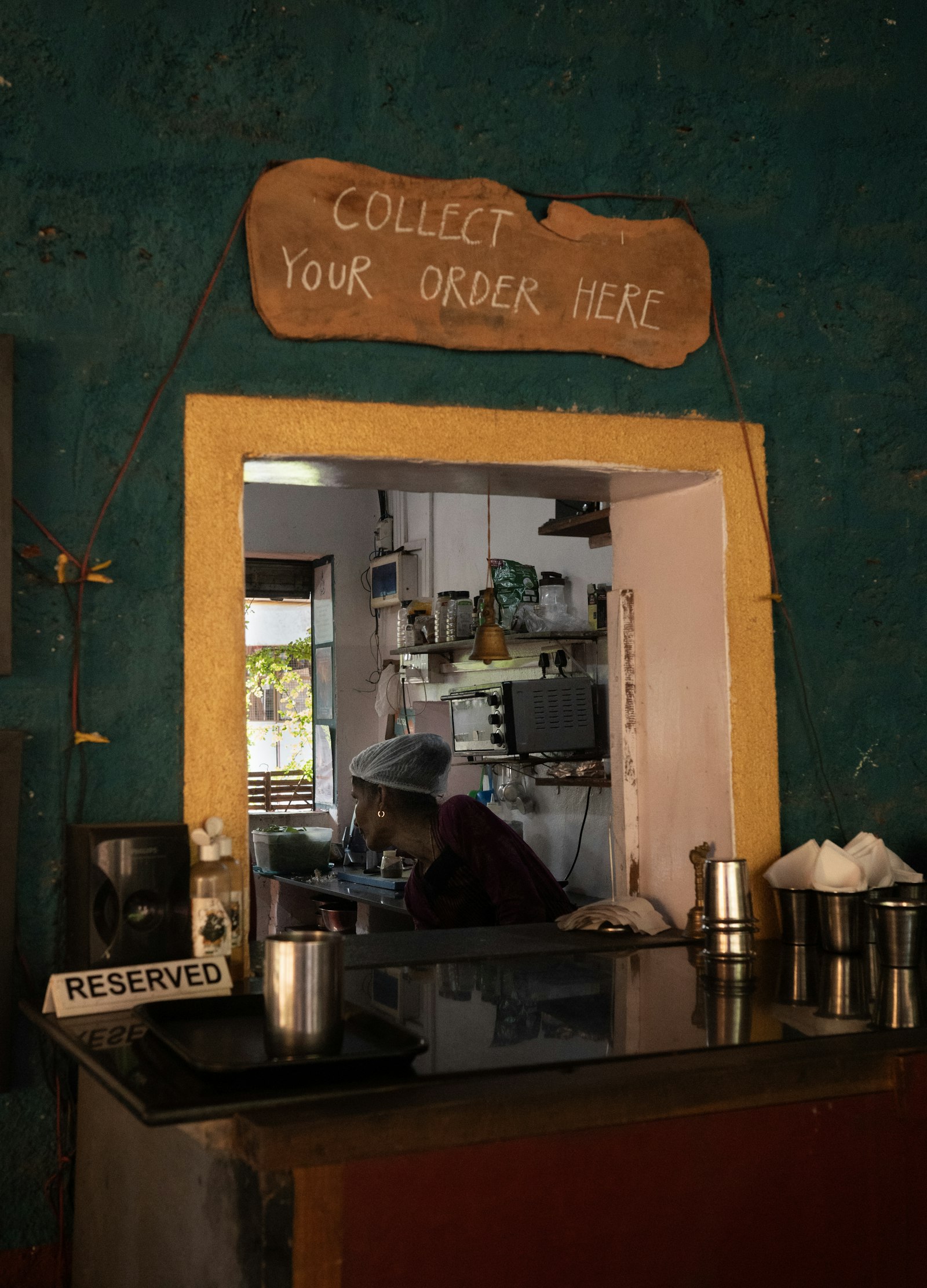 A small restaurant with a cook visible through the kitchen window