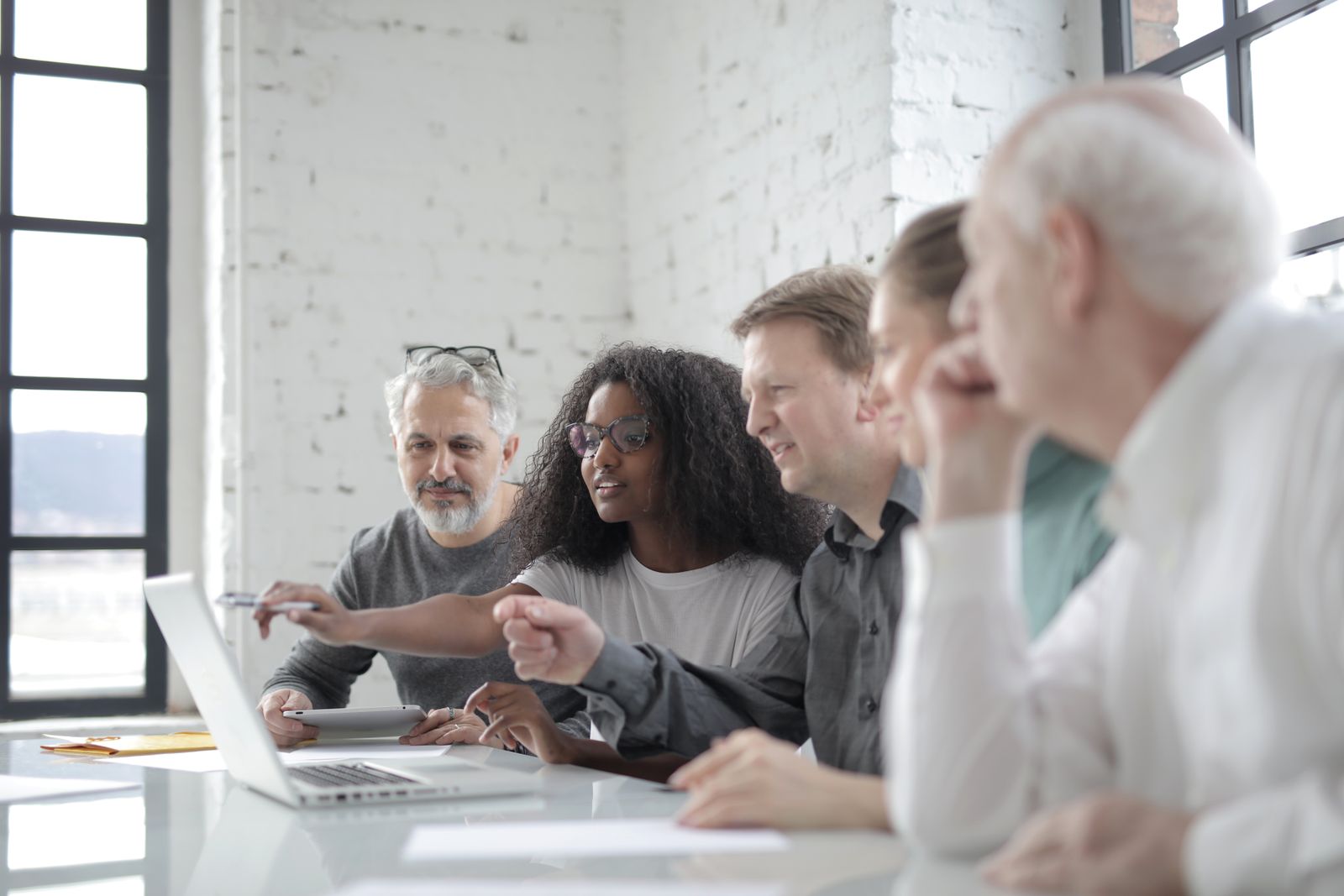 A group of colleagues discussing a project around a laptop in a bright office