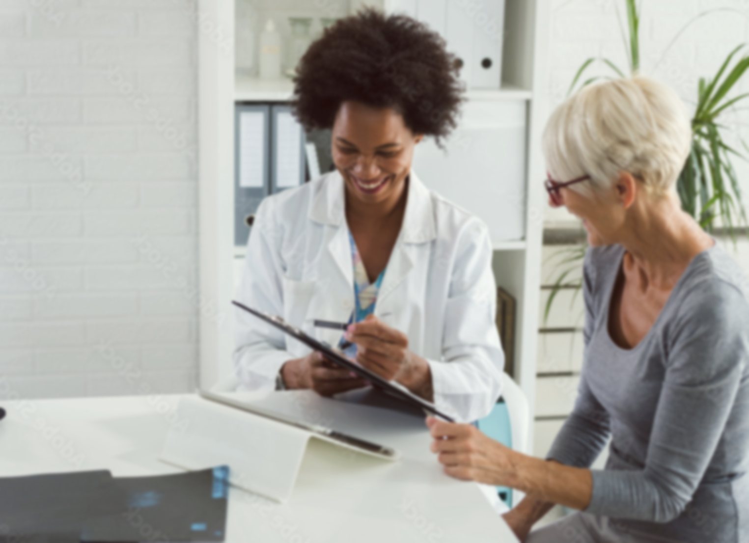 A clinician in a white coat reviews a care plan on a clipboard with an older patient at a desk