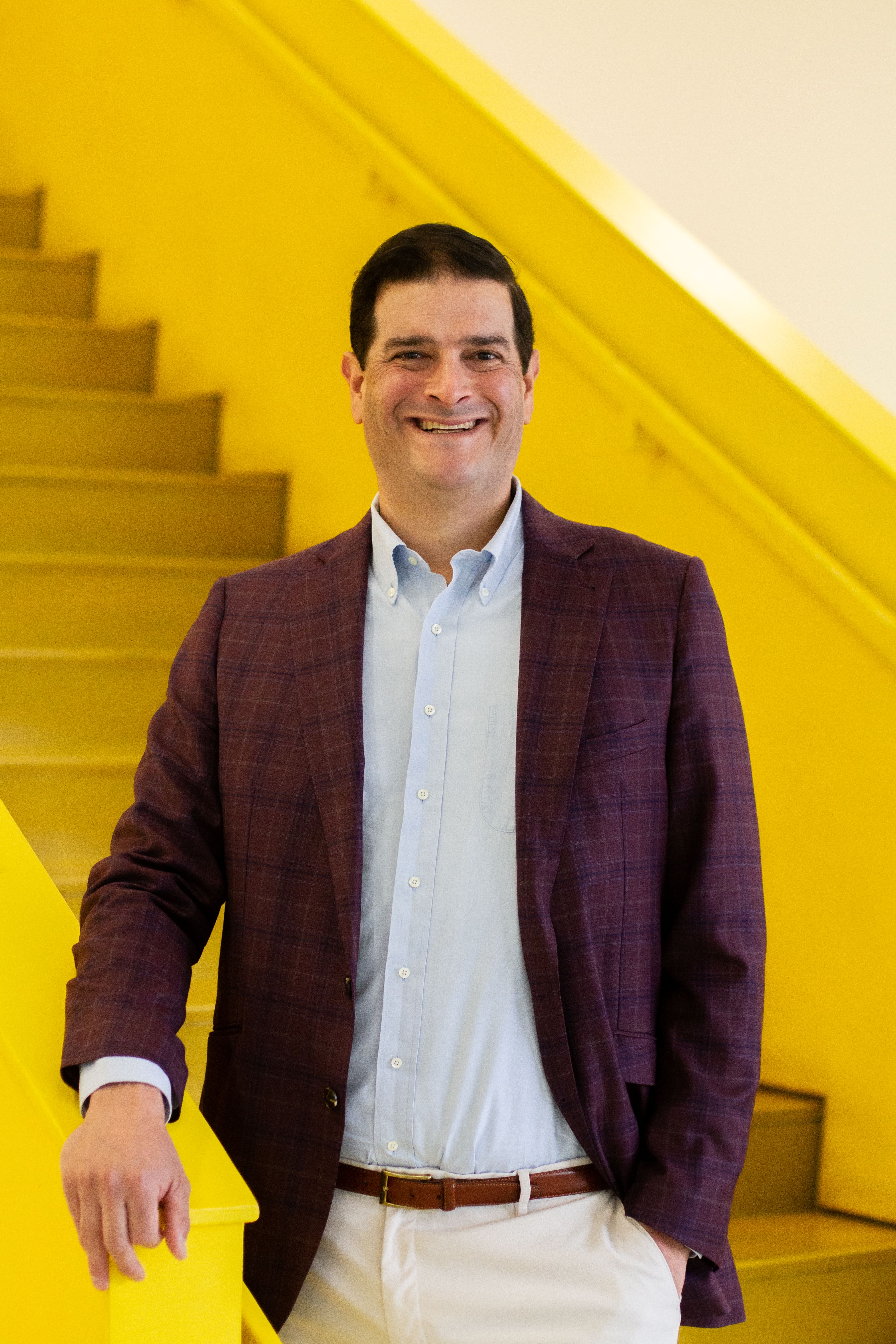 Khaner Walker, founder of ArcSense, smiling on a yellow staircase