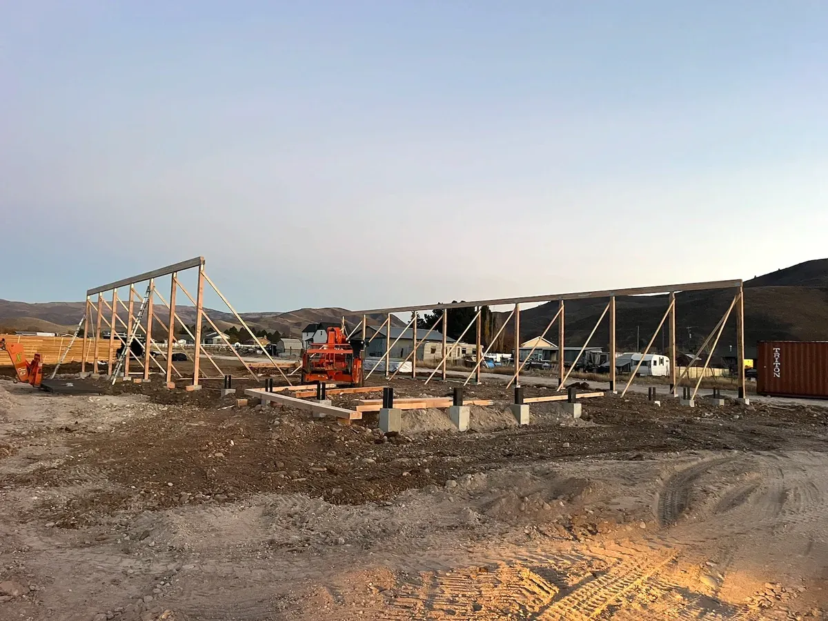 Leveled building site with concrete pier footings and post-frame walls going up