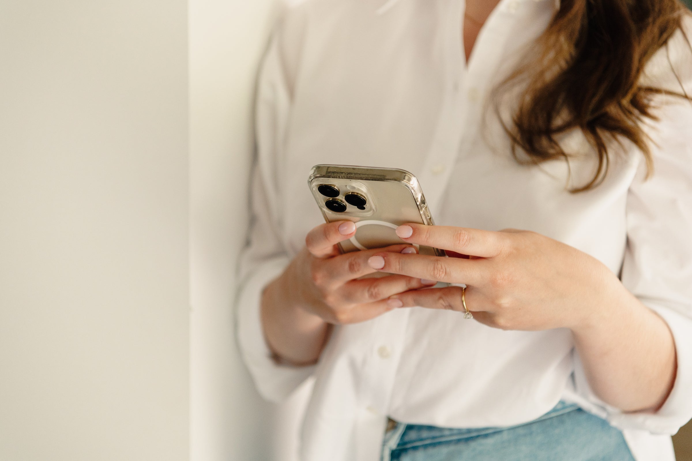 Anke in een wit hemd met haar smartphone in de hand