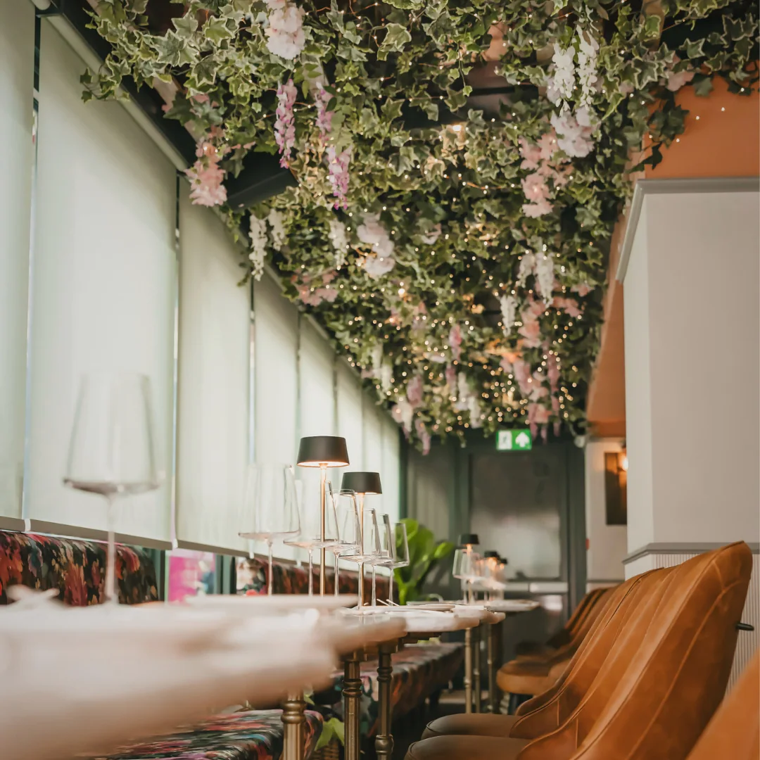 Tables beneath hanging flowers at Bazaar
