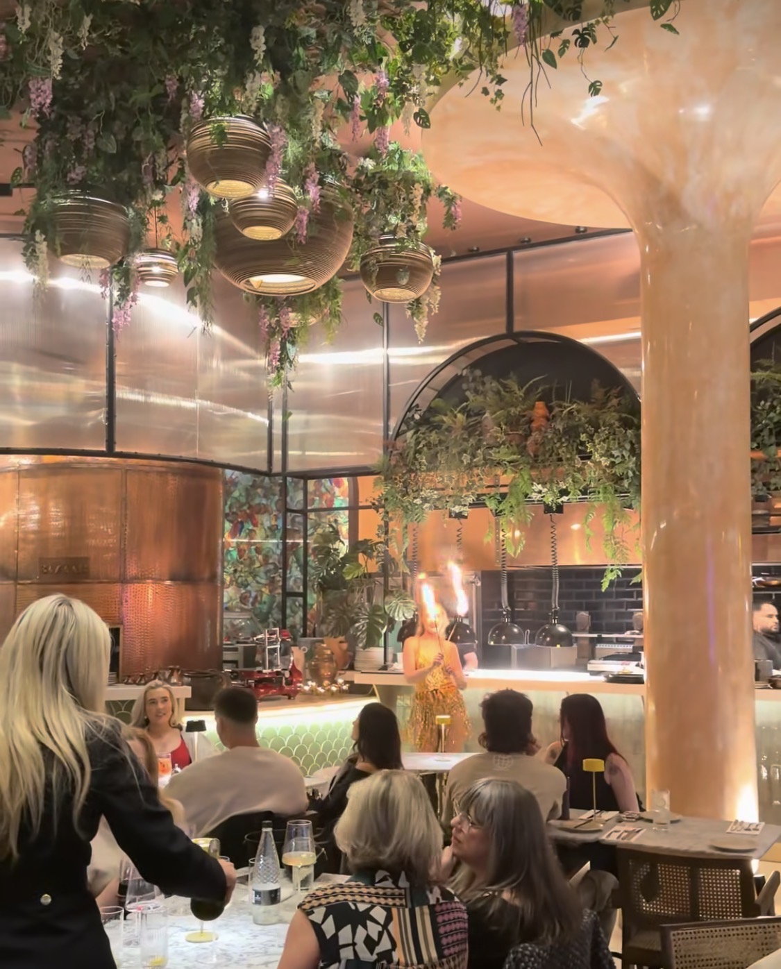 Fire performer entertaining diners beneath the hanging flowers at Bazaar