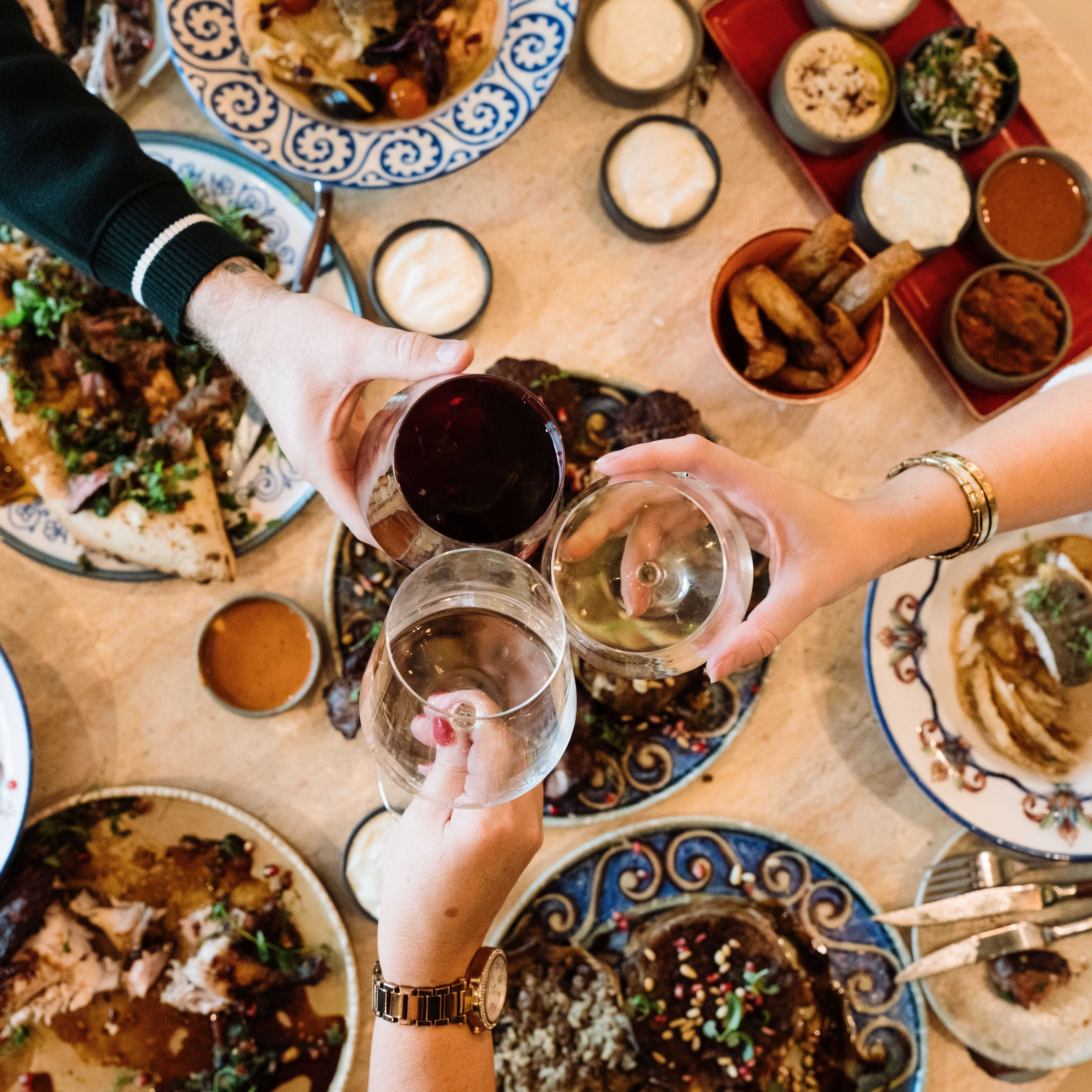 Guests raising a toast over a table of sharing dishes at Bazaar