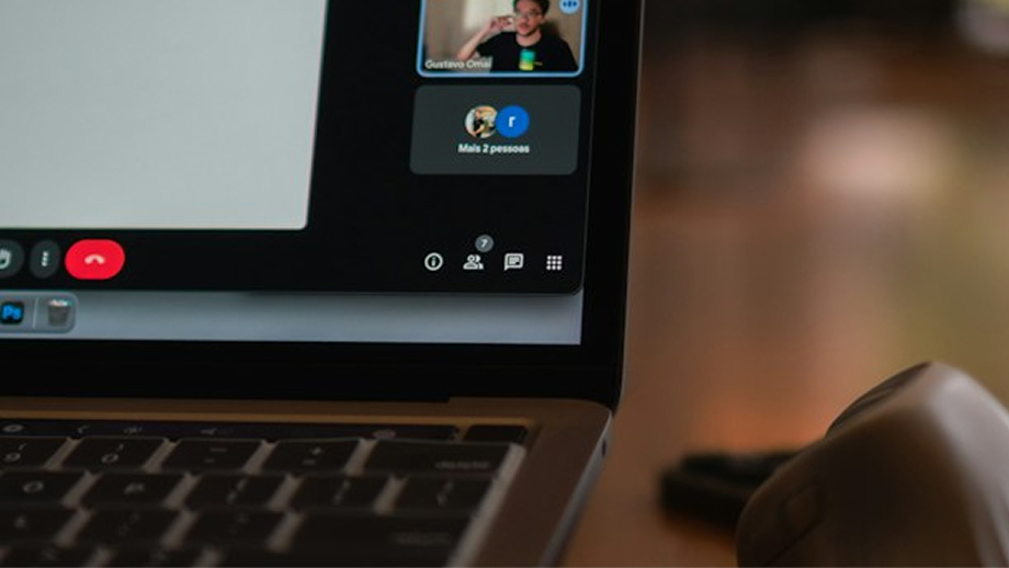 Close-up of a laptop keyboard and screen showing a video call interface with a participant's video thumbnail and call control icons.