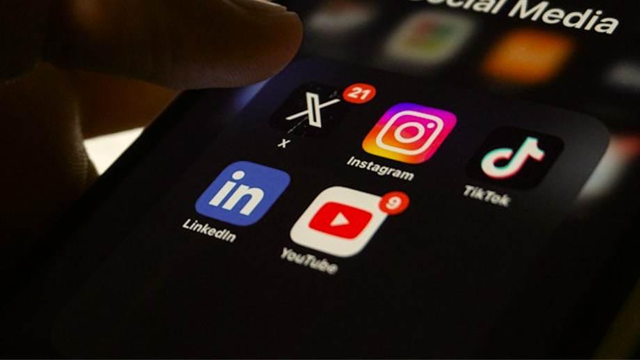 Close-up of a smartphone screen showing a folder labeled Social Media with app icons for X, Instagram with 21 notifications, TikTok, LinkedIn, and YouTube with 9 notifications.