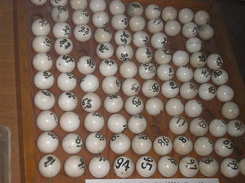A wooden tray of hand-numbered lottery balls