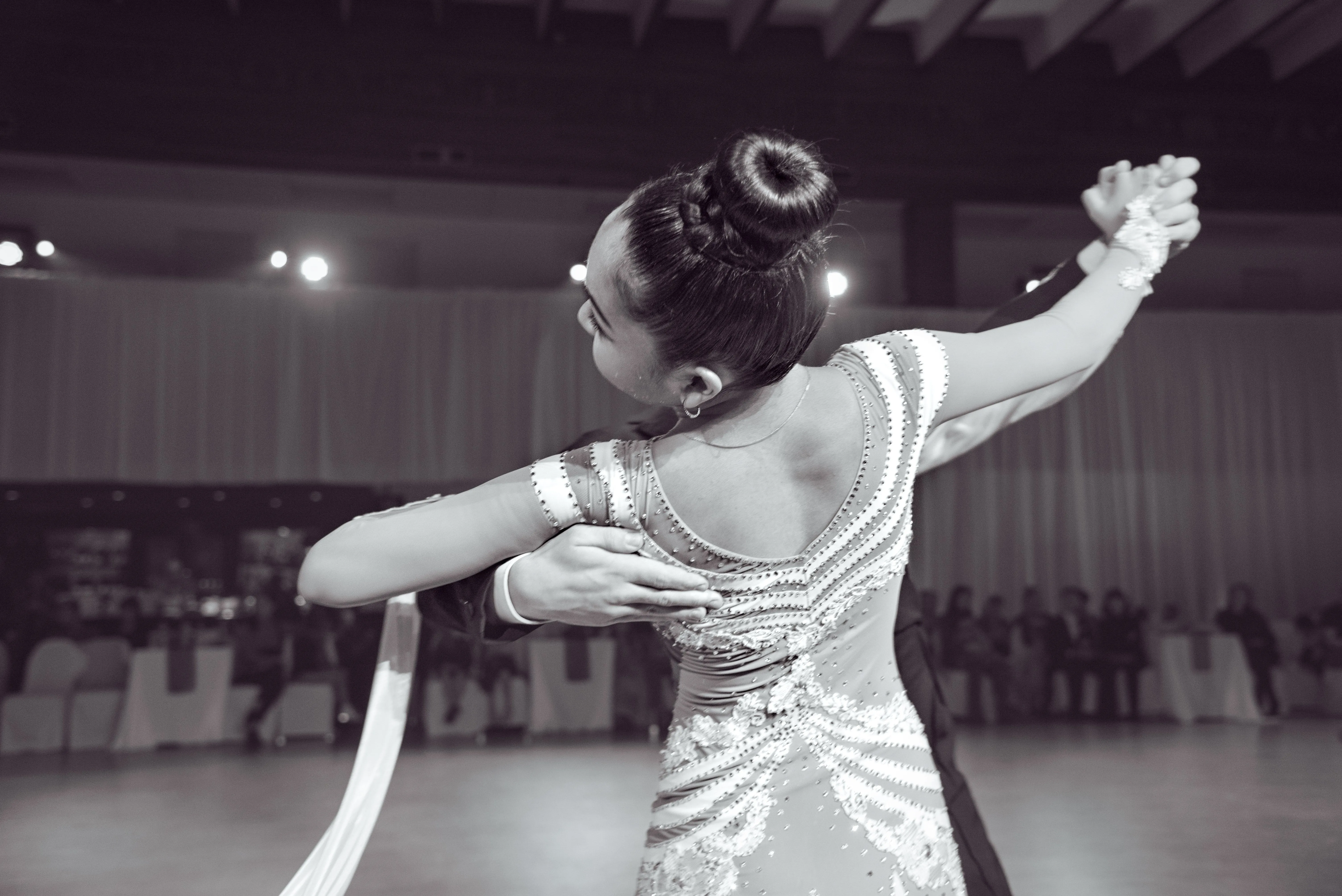 Close view of a ballroom partnership, with crystal detailing and joined hands.