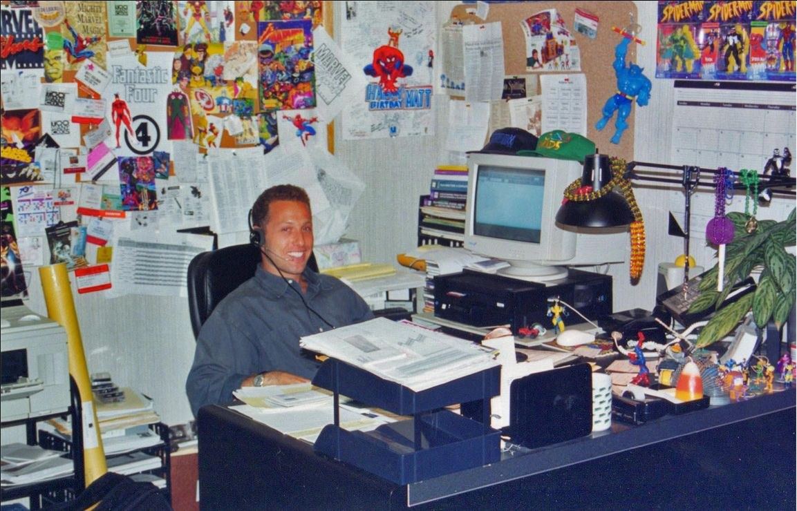 A young executive at a desk covered in comic book posters, 1990s