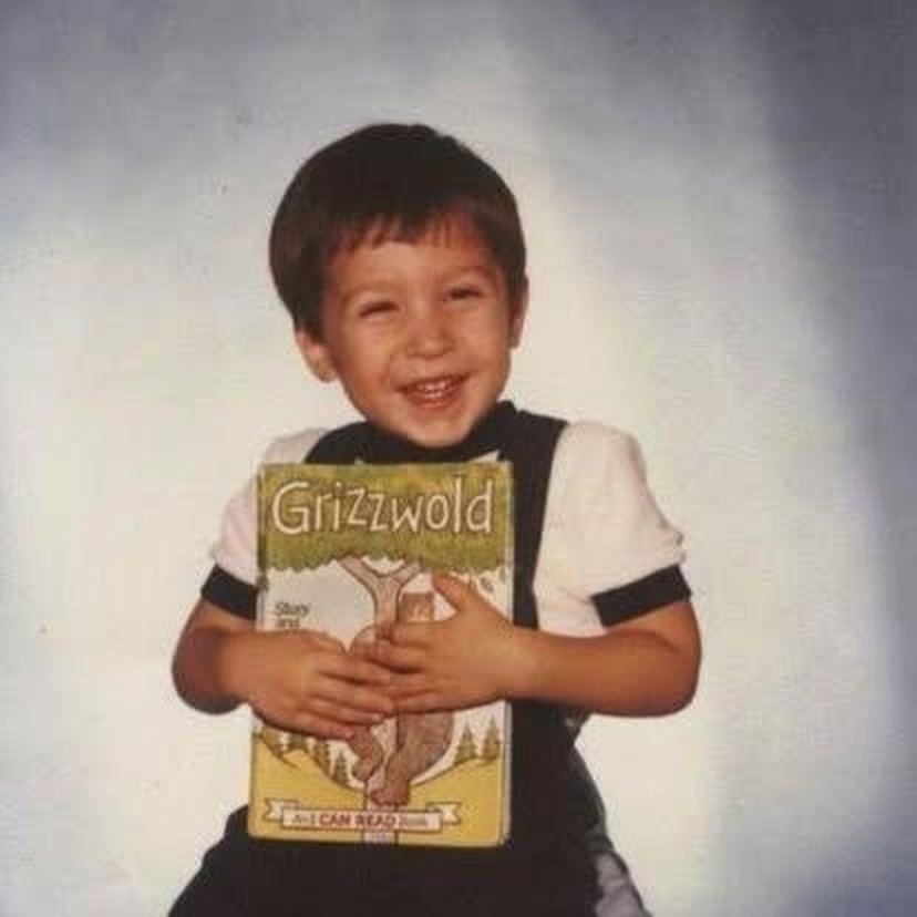 A small boy holding a picture book, smiling at the camera