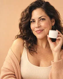 Raya member smiling and holding a jar of hormone cream during her video check-in