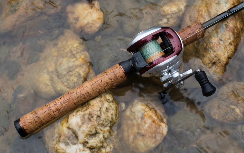 Fishing reel and rod resting over shallow river stones