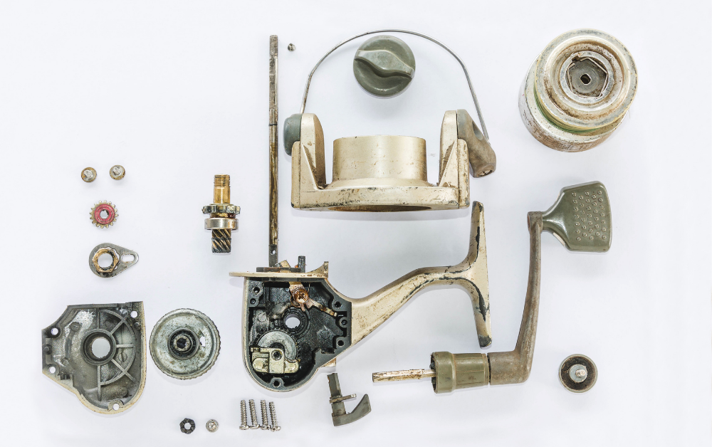 Disassembled fishing reel with separate mechanical parts arranged for inspection