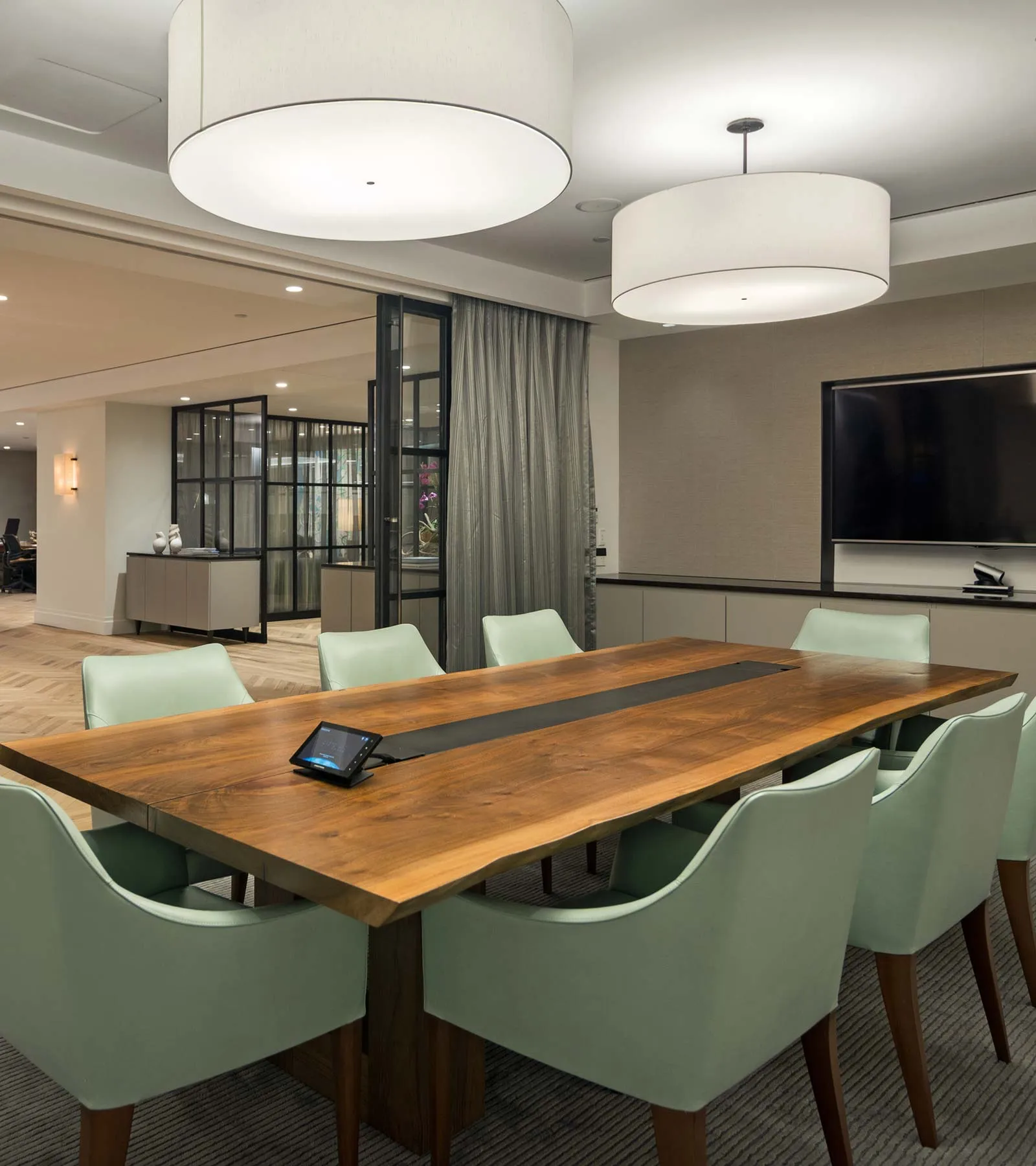 The Commons Capital conference room, with a long wooden table, chairs and a presentation screen.