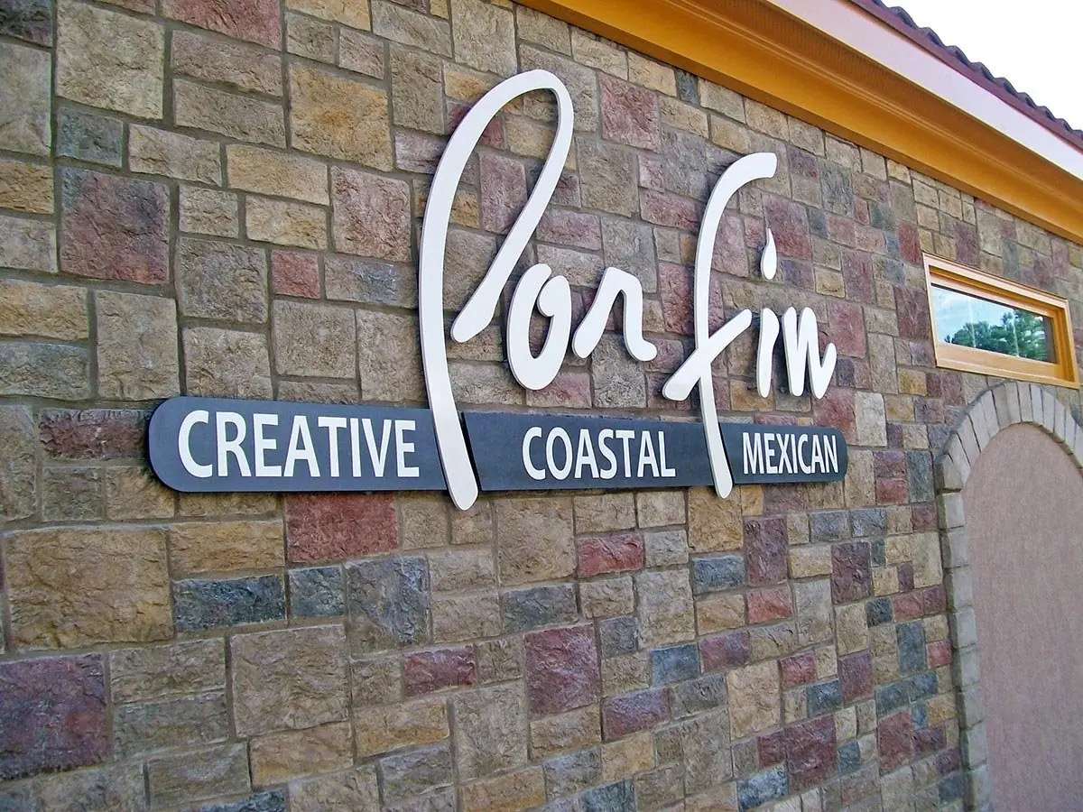 Dimensional 3D letter sign for Por Fin restaurant mounted on a stone facade