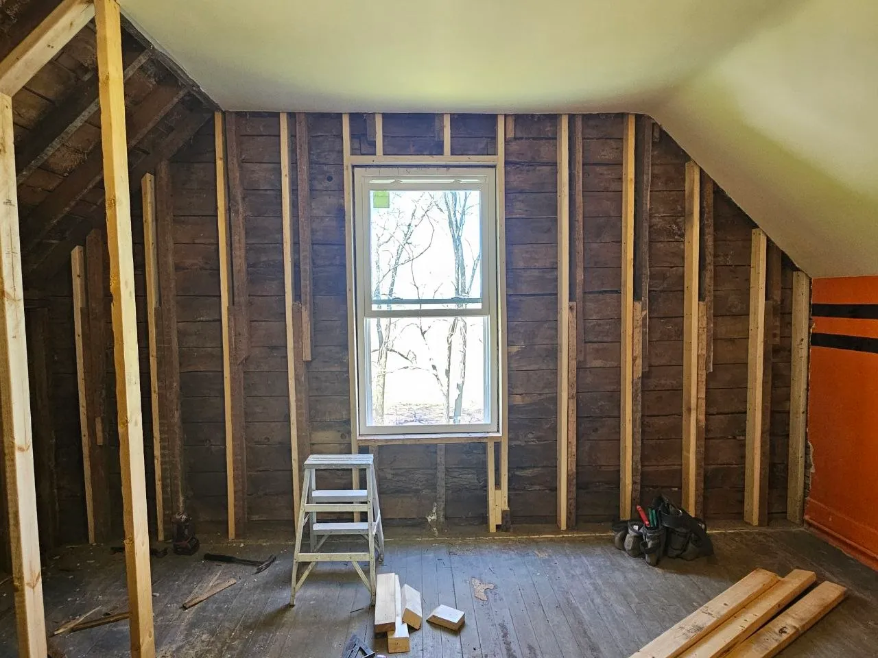 Attic bedroom before renovation, bare boards and new framing