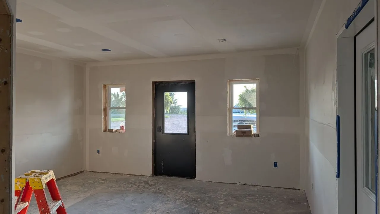 Taped drywall room with entry door and windows