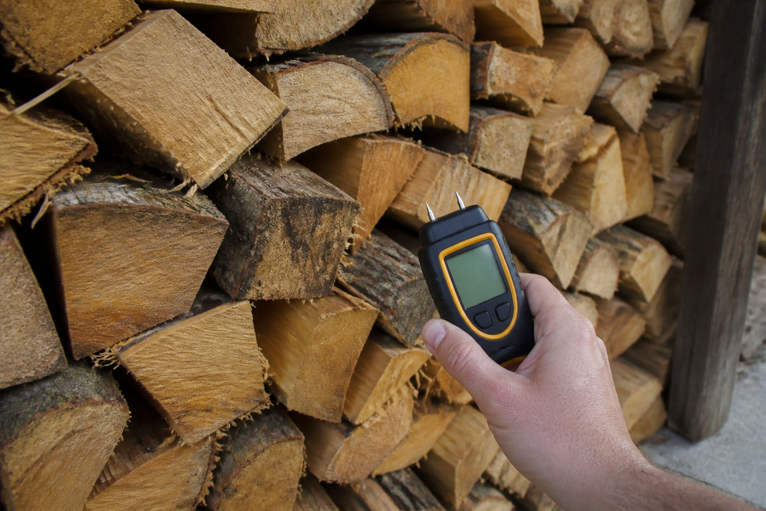 Humidimètre planté dans une bûche pour vérifier que le bois de chauffage est sec