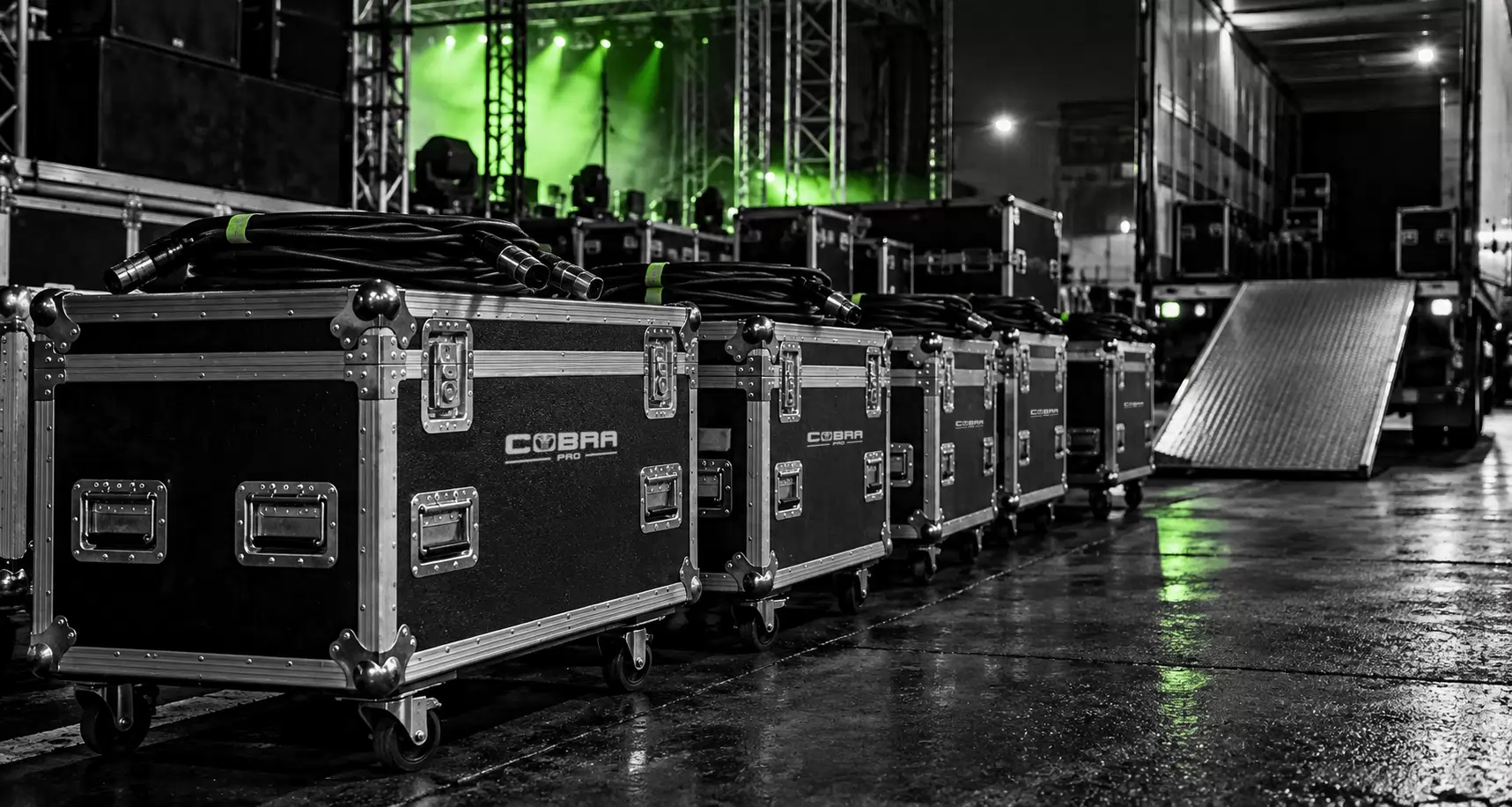 Flight cases and coiled cables lined up at a backstage loading dock