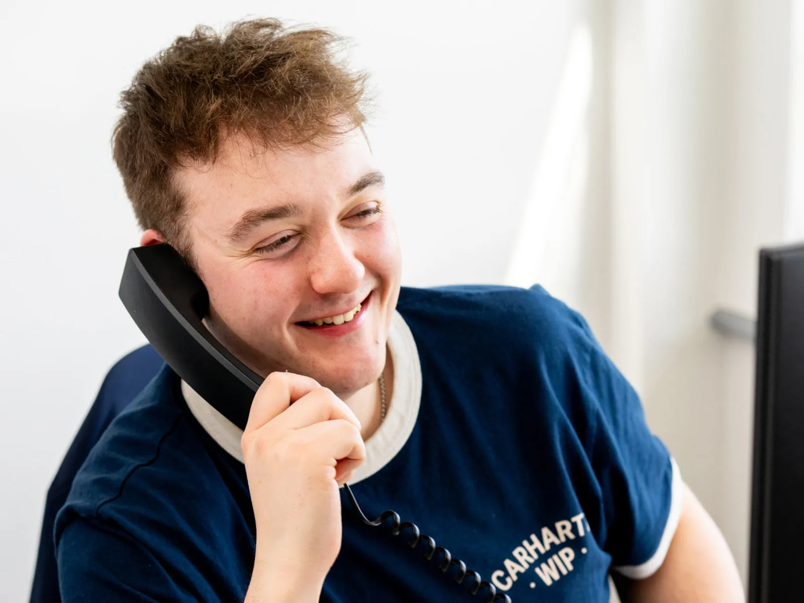 A member of the Pollard Media team smiling on a phone call at his desk