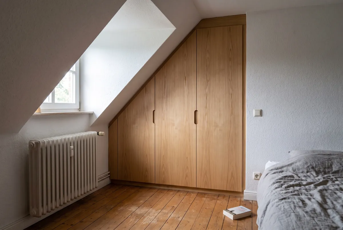 Einbauschrank aus geölter Esche mit drei Türen, der unter einer Dachschräge im Schlafzimmer eines Altbaus sitzt