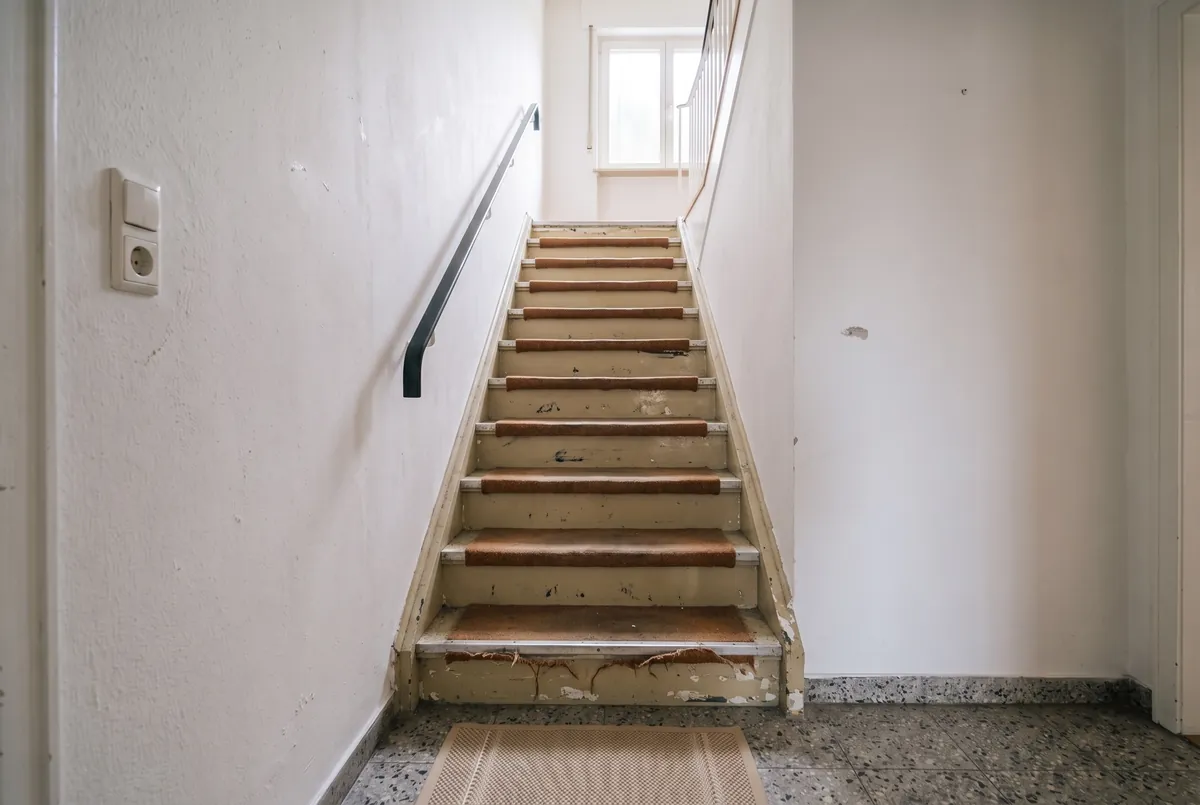 Die Treppe vorher, mit altem Teppich auf den Stufen und ausgetretenen Kanten