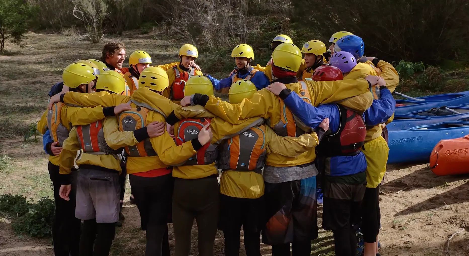 The crew in a team huddle by the river