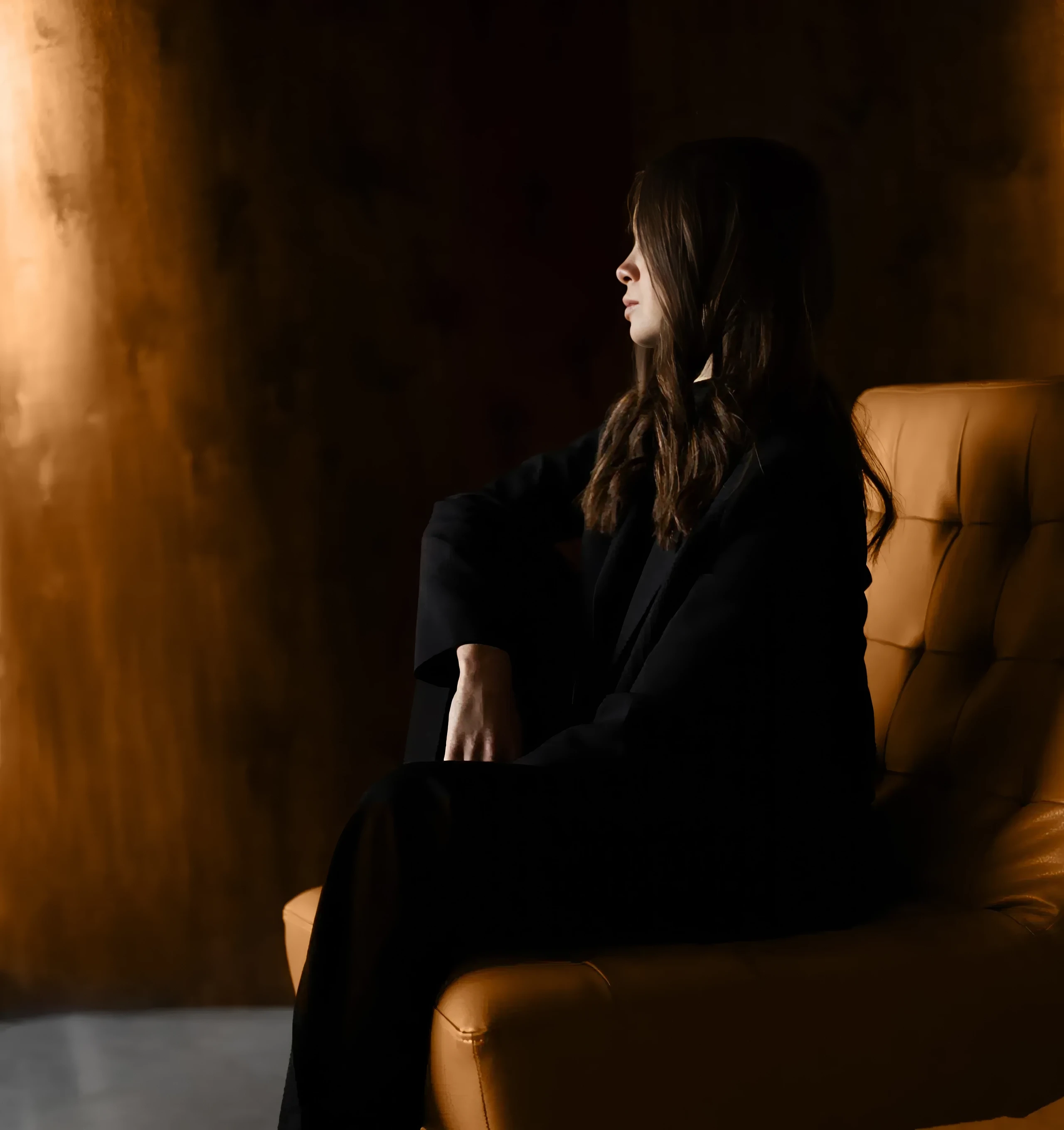 Tetiana Liubytska sitting in a leather armchair in warm light