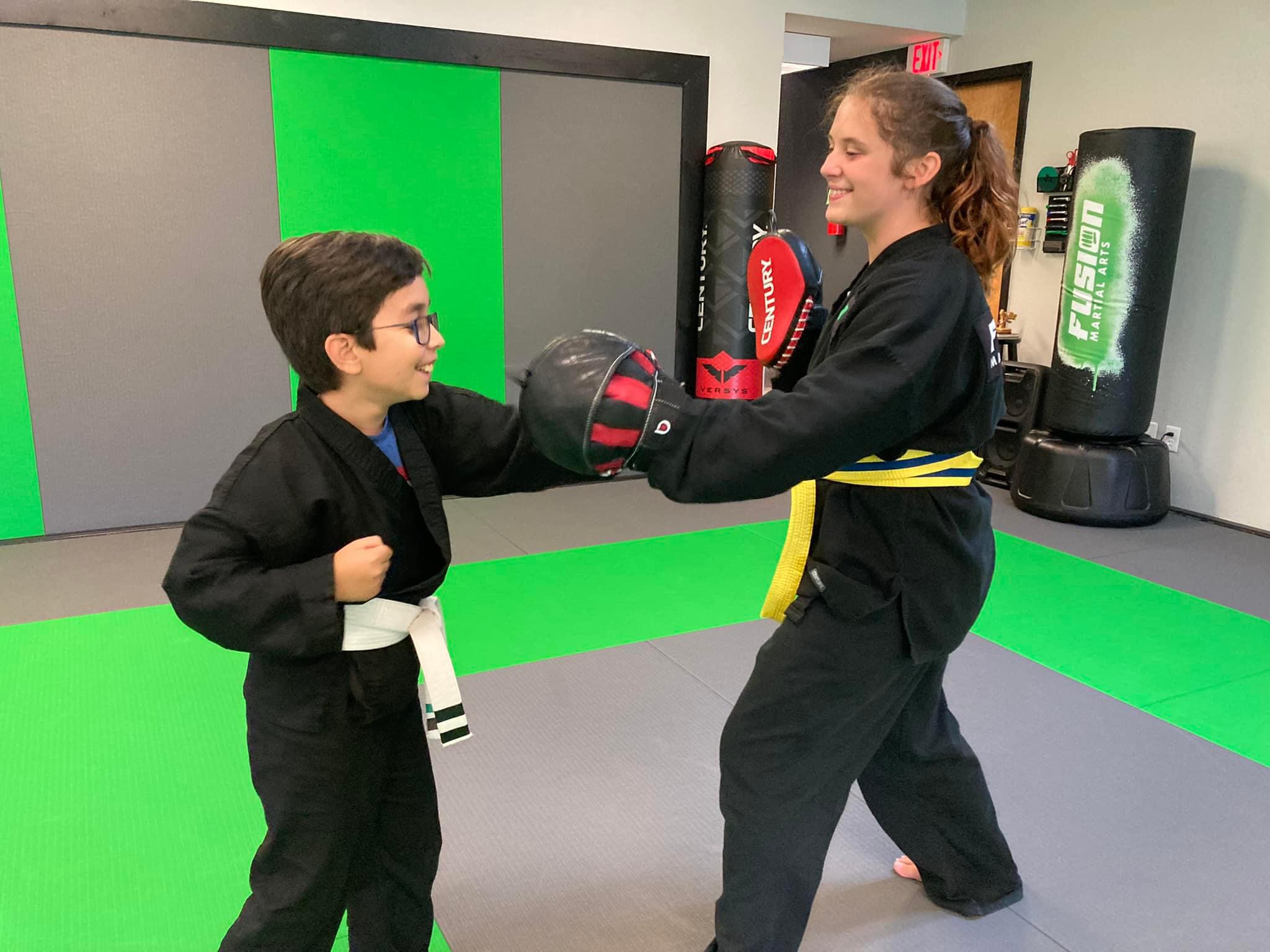 Kids training with partners on pads at Fusion Martial Arts in Bloomington, IL