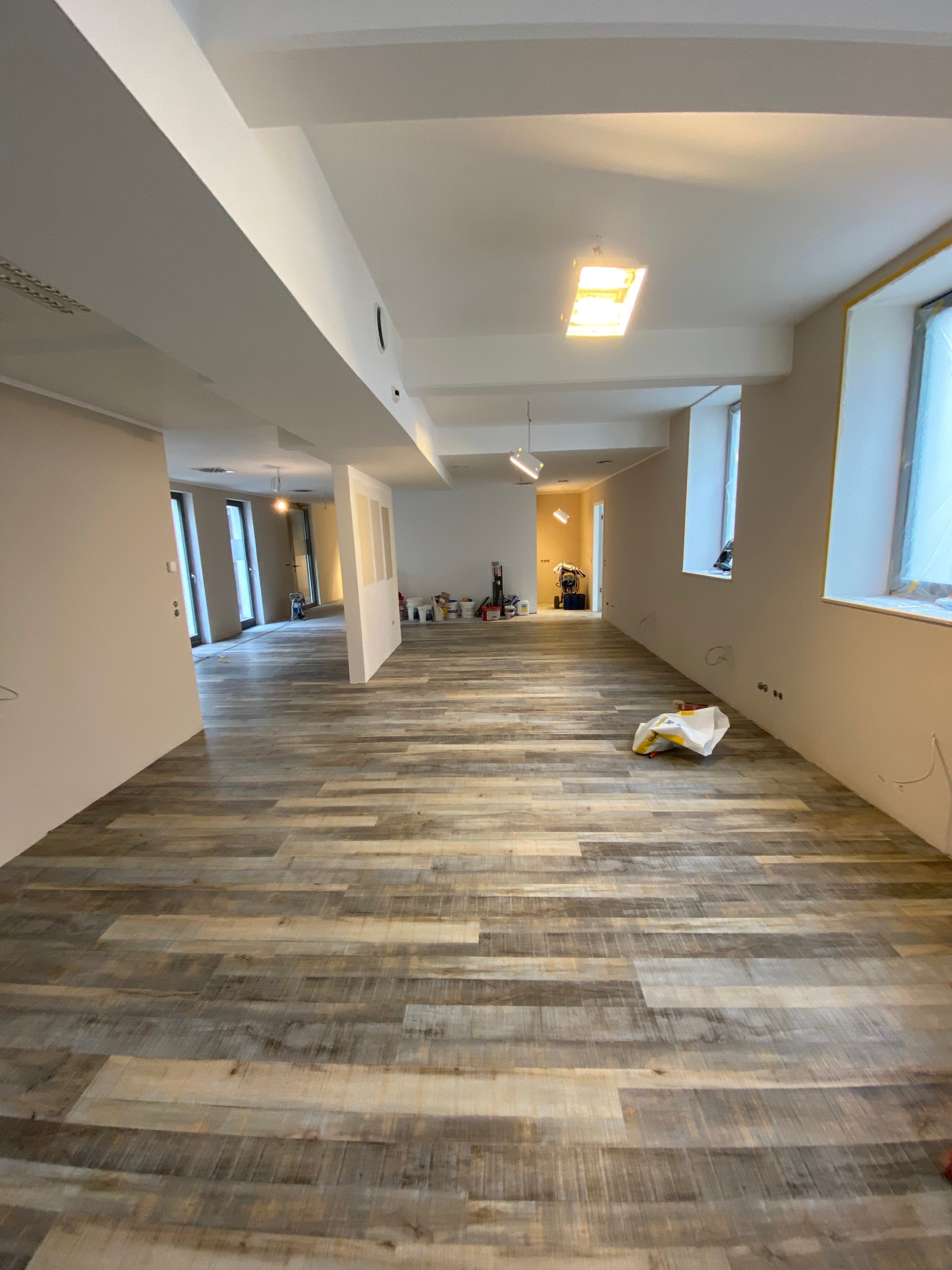 Maler beim Streichen einer Wand in einem Altbauraum mit Sprossenfenster