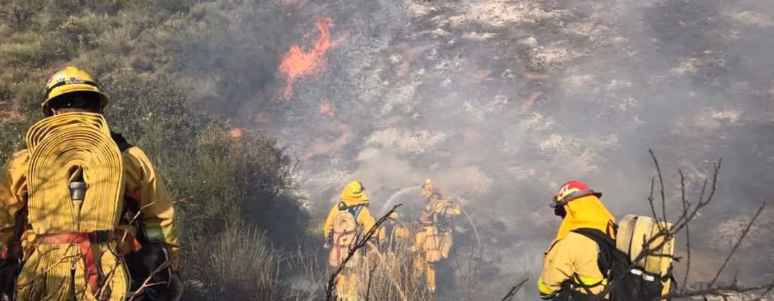 Firefighters battling a brush fire on a hillside