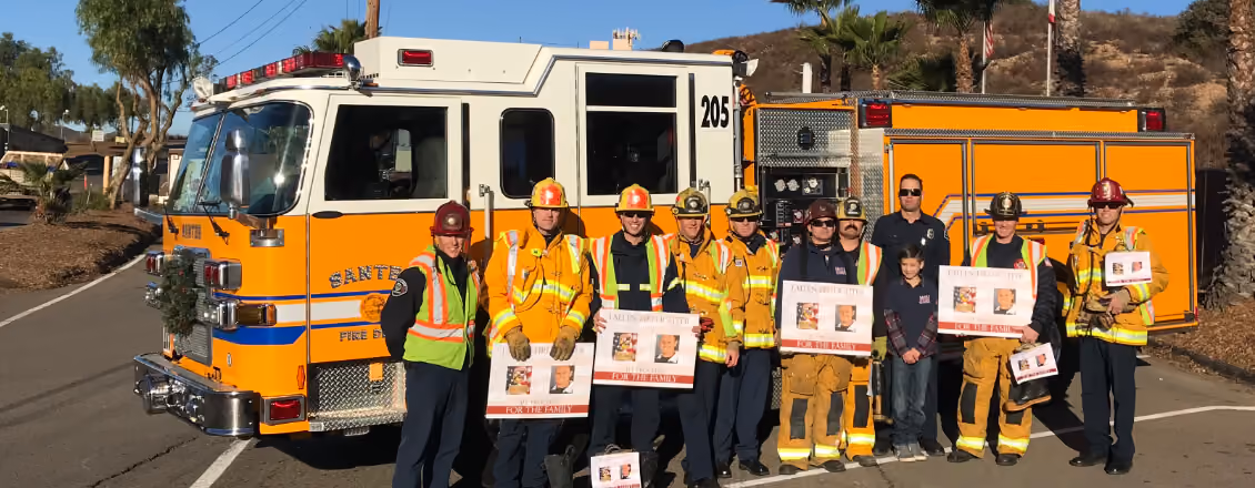 Santee firefighters in turnout gear standing in front of an orange Santee fire engine