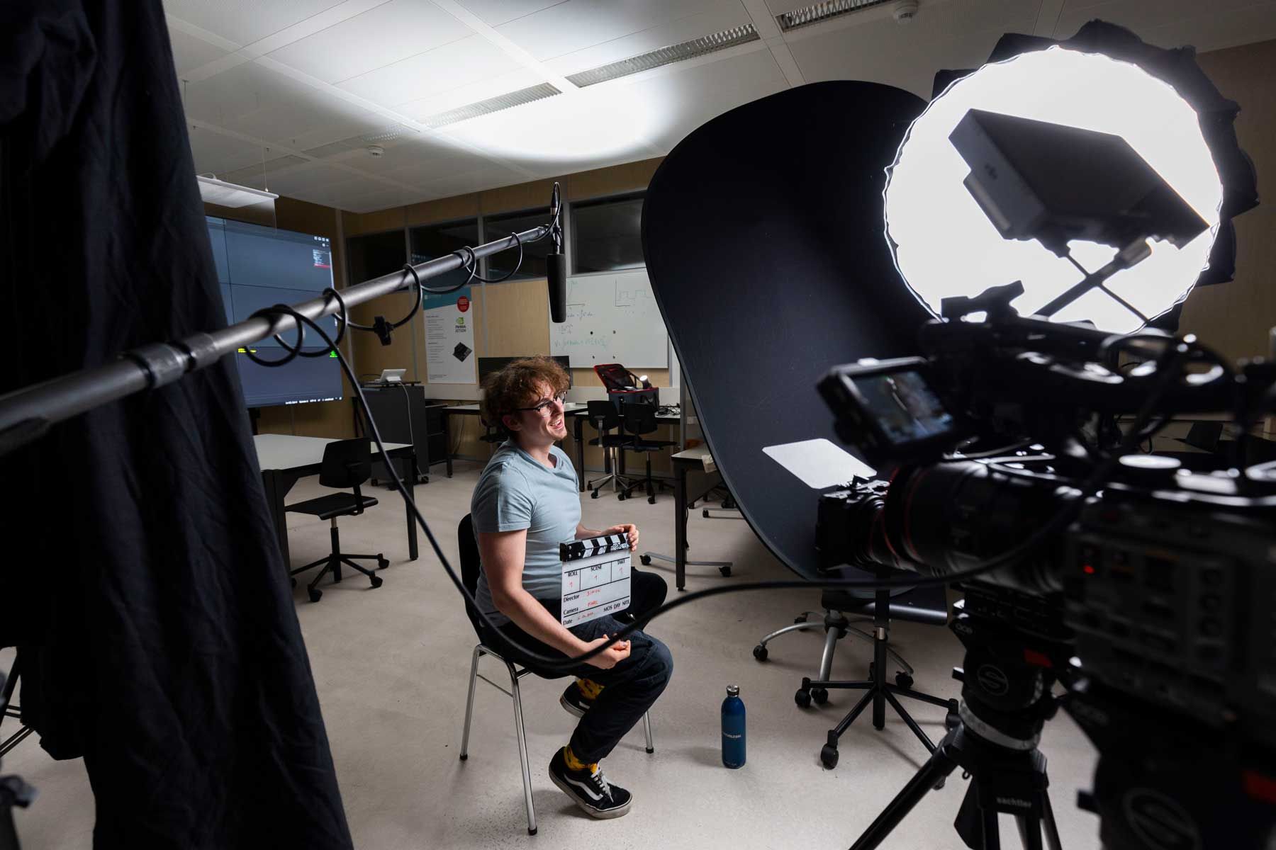 Interviewpartner mit Filmklappe vor Kamera und Softbox