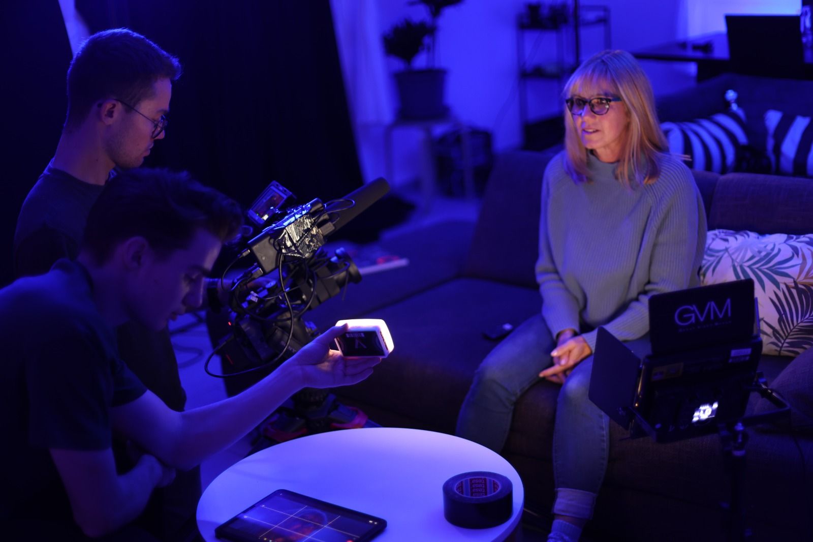 Kameramann filmt eine Frau im Interview, beleuchtet mit blauem Licht