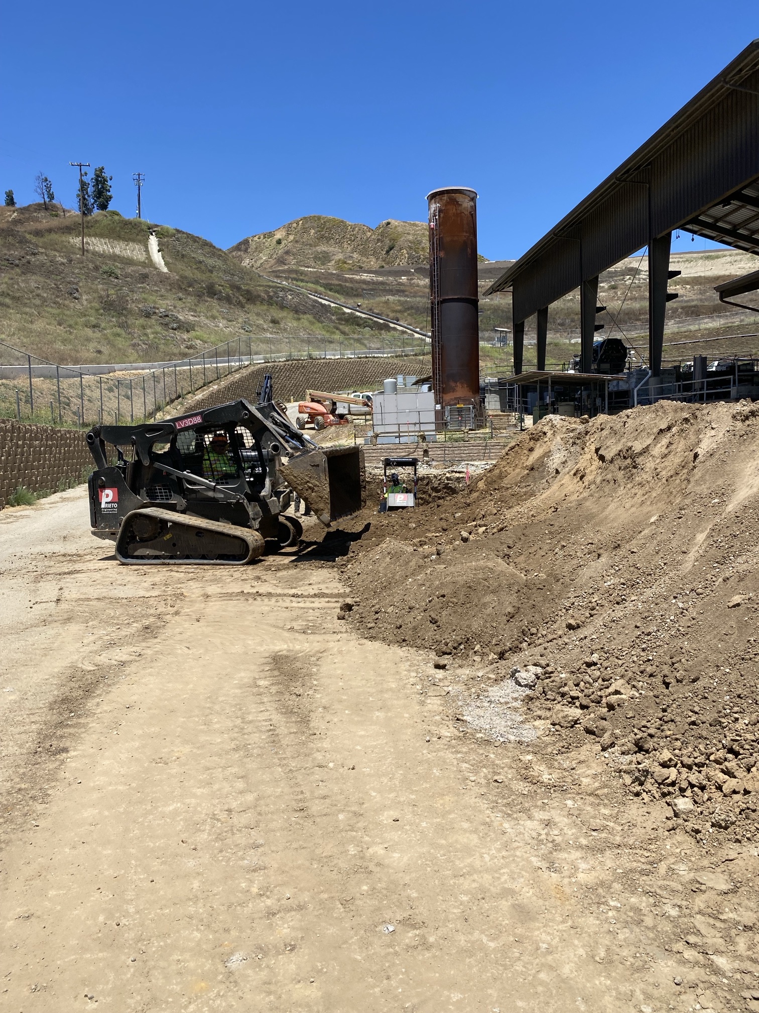 Prieto track loader grading beside a landfill gas flare stack