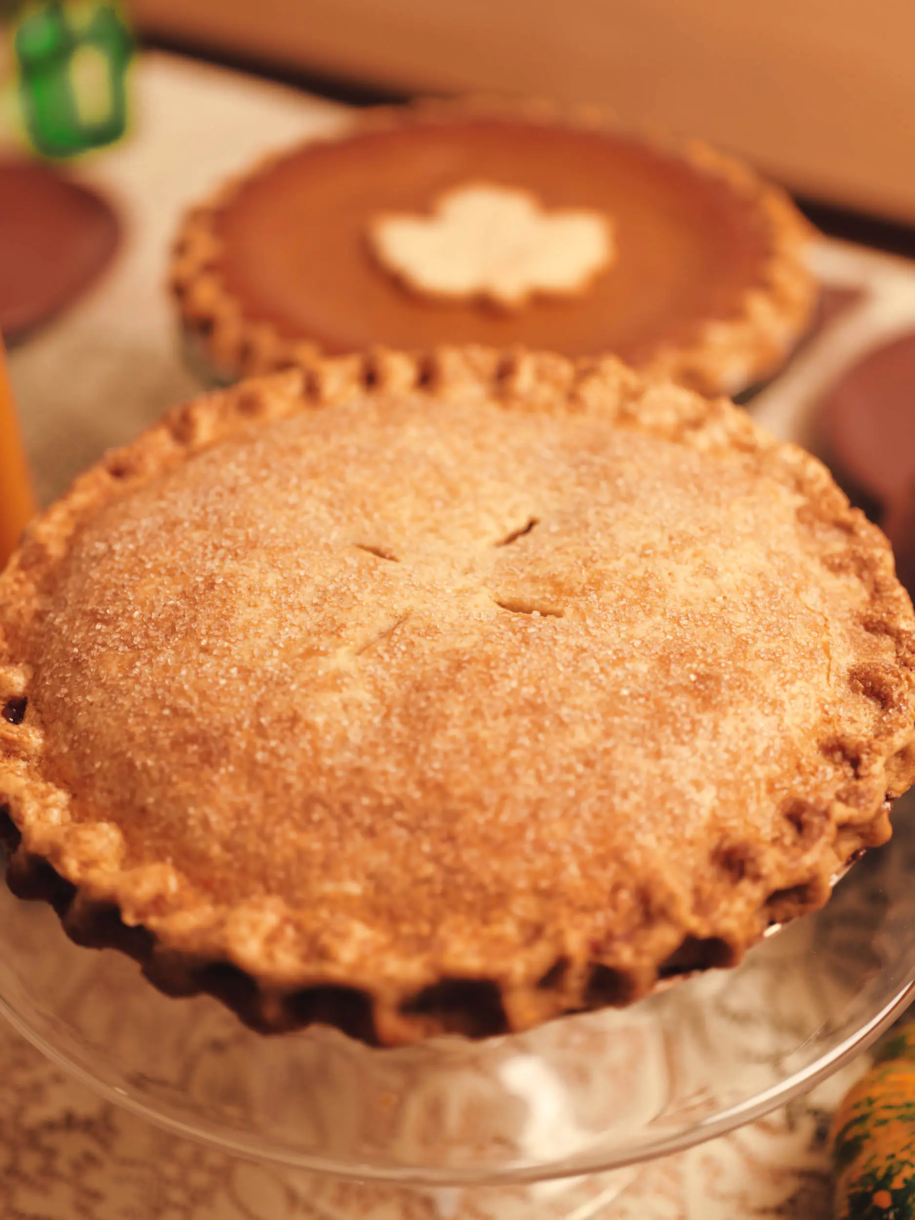 Double crust pie with a pumpkin pie behind it