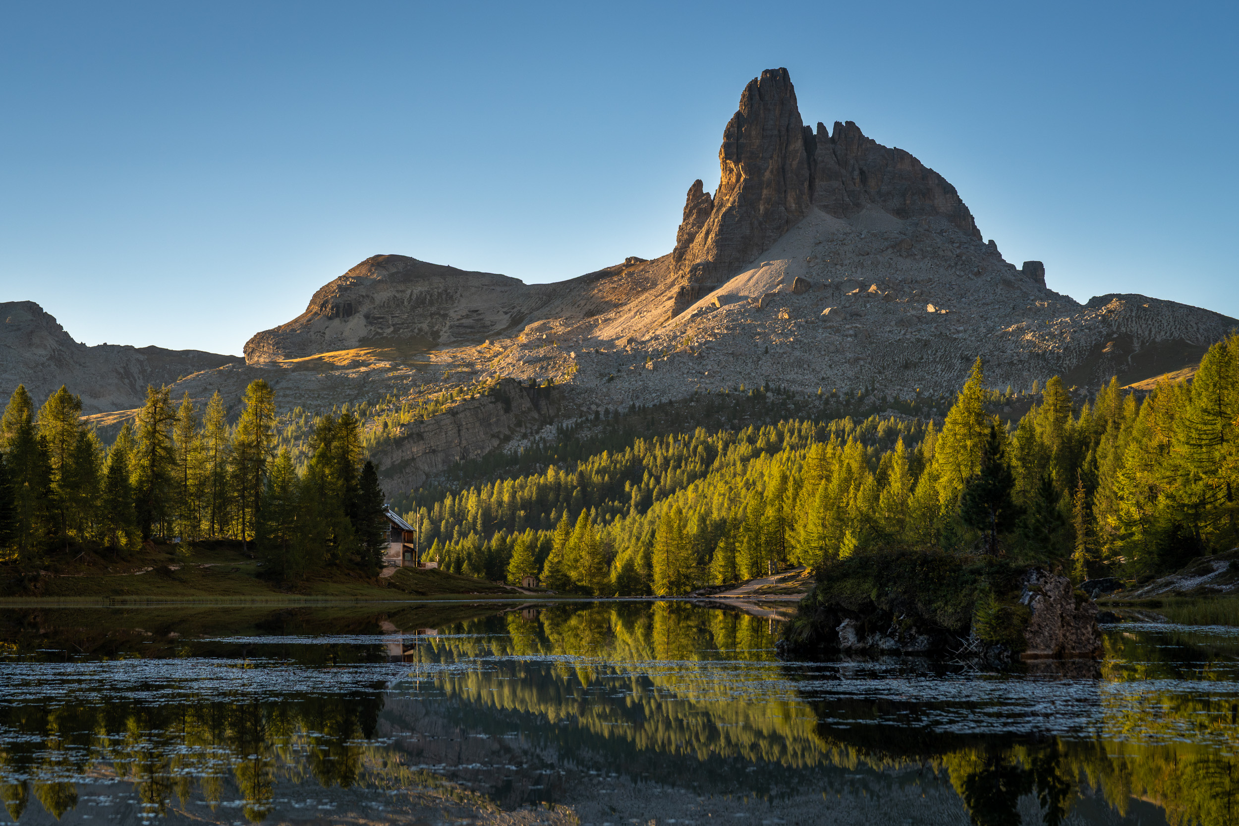 Becco di Mezzodì spiegelt sich im Lago Federa, umgeben von goldenen Lärchen