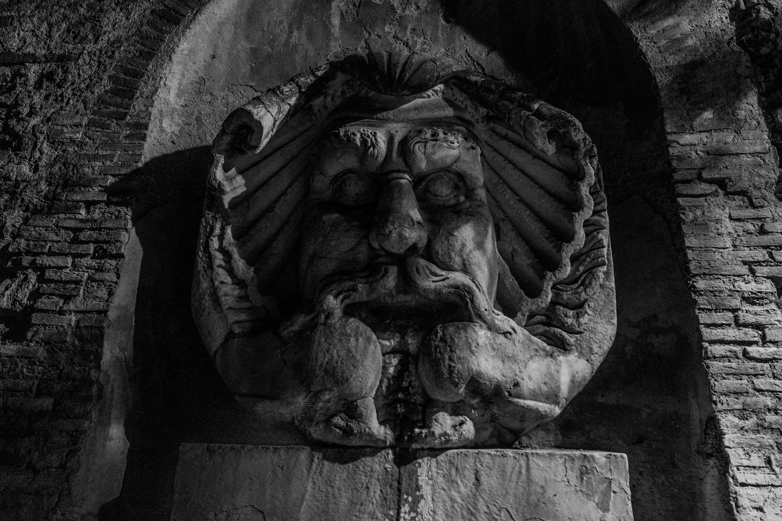 Steinerne Maske eines Brunnens in Schwarzweiß