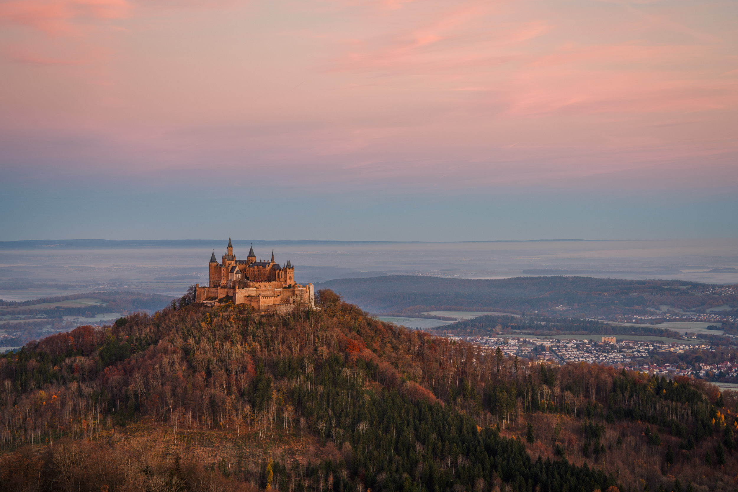 Burg Hohenzollern auf dem herbstlichen Bergkegel unter rosa Morgenhimmel