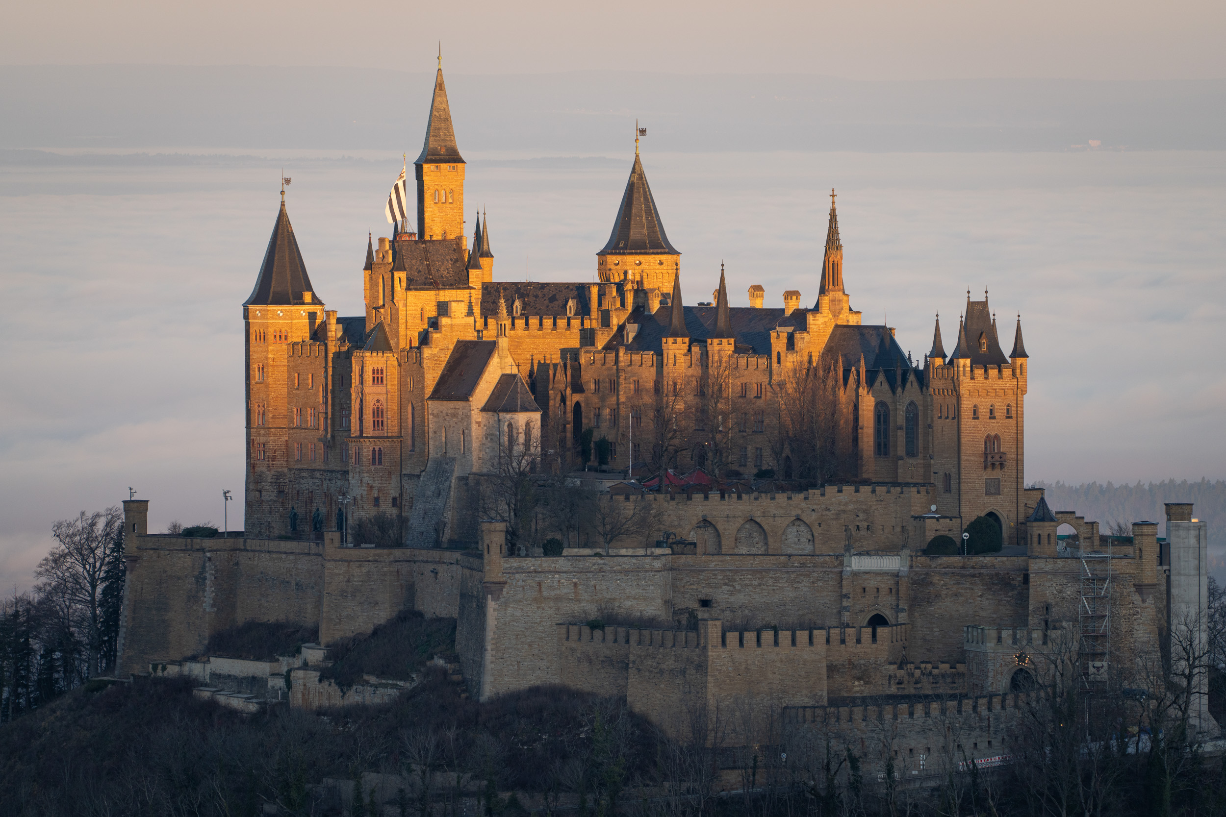 Türme und Mauern der Burg Hohenzollern im warmen Morgenlicht vor Nebel