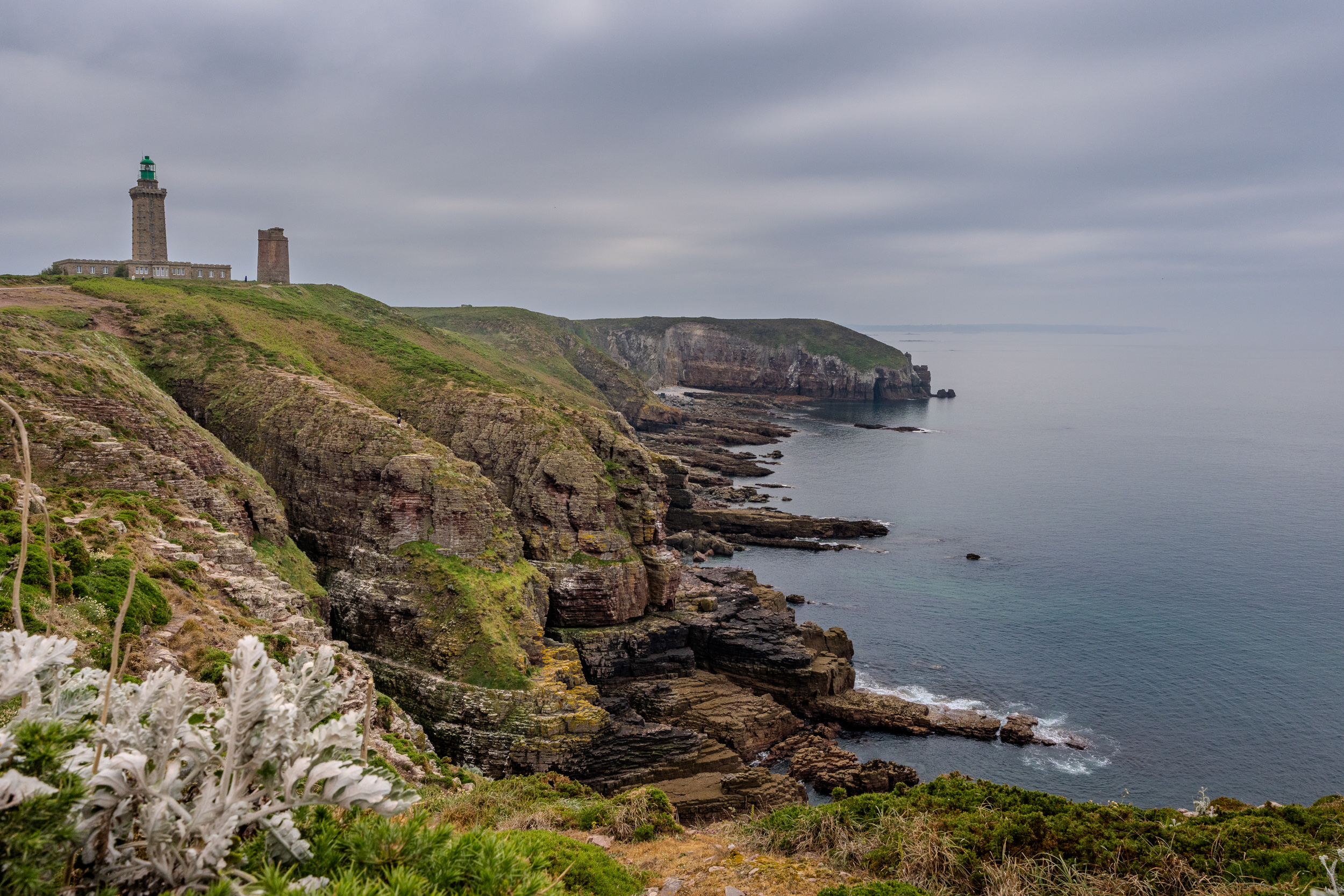 Steilküste am Cap Fréhel mit Leuchtturm unter grauem Himmel
