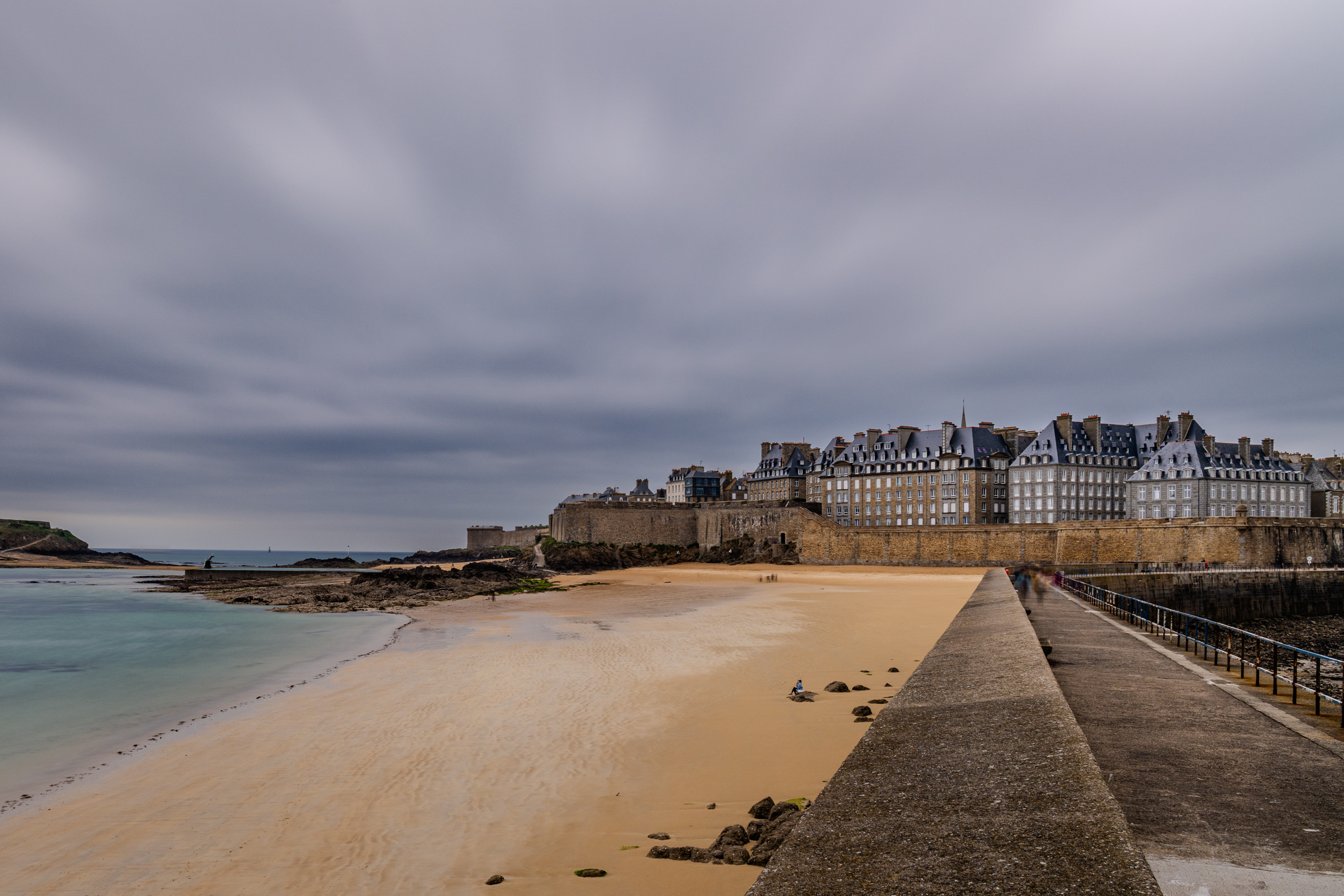 Strand und Stadtmauer von Saint-Malo unter dunklen Wolken