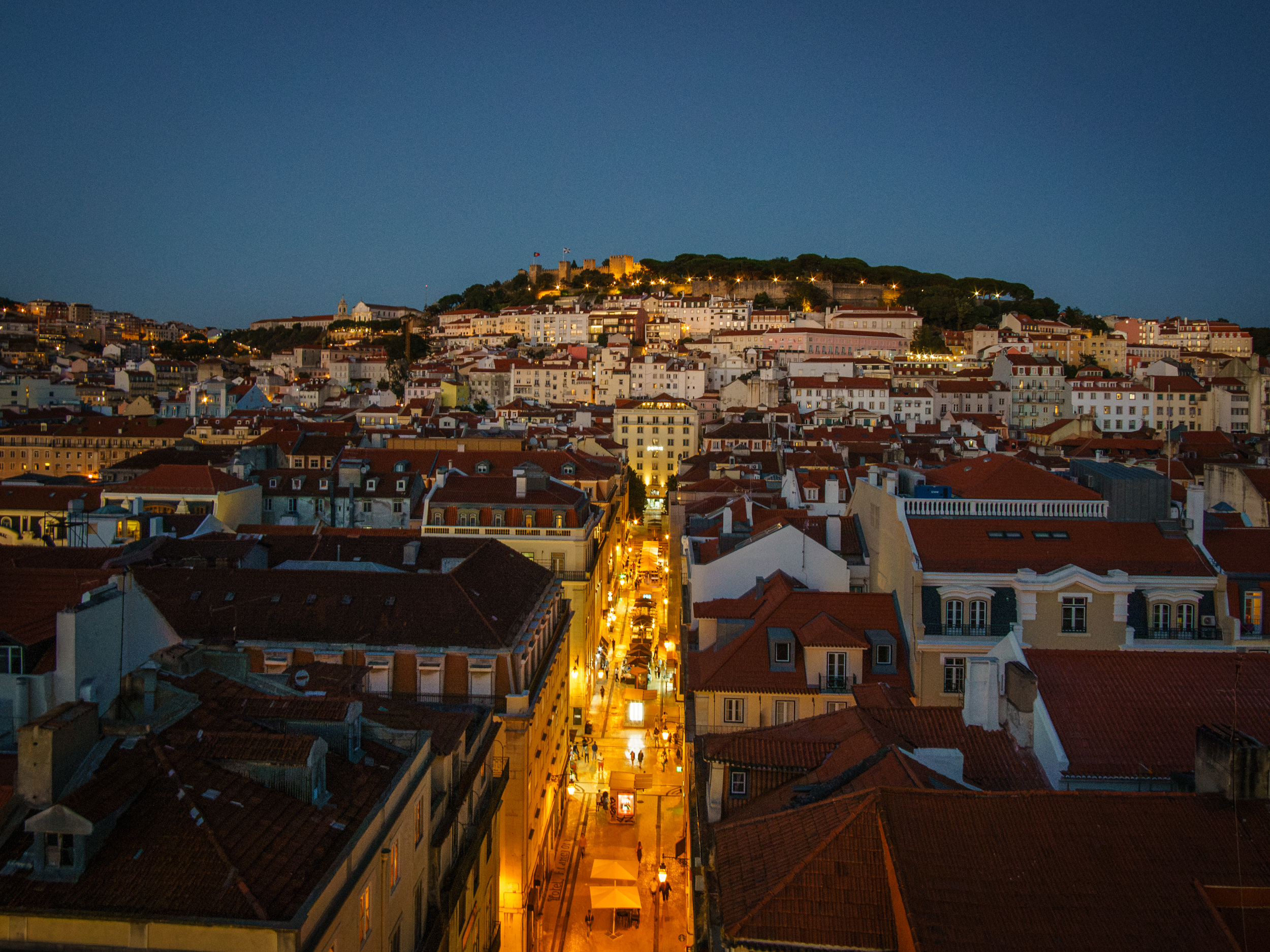 Beleuchtete Baixa bei Nacht, darüber das Castelo de São Jorge