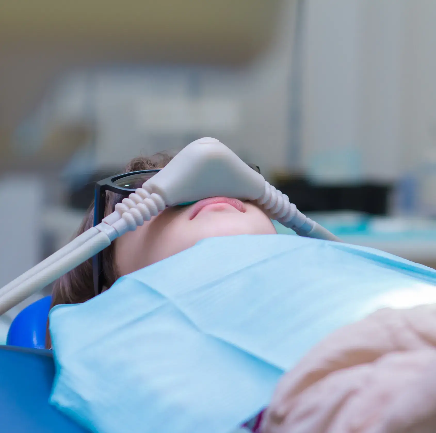 A woman laying in a hospital bed with an oxygen tube attached to her head.