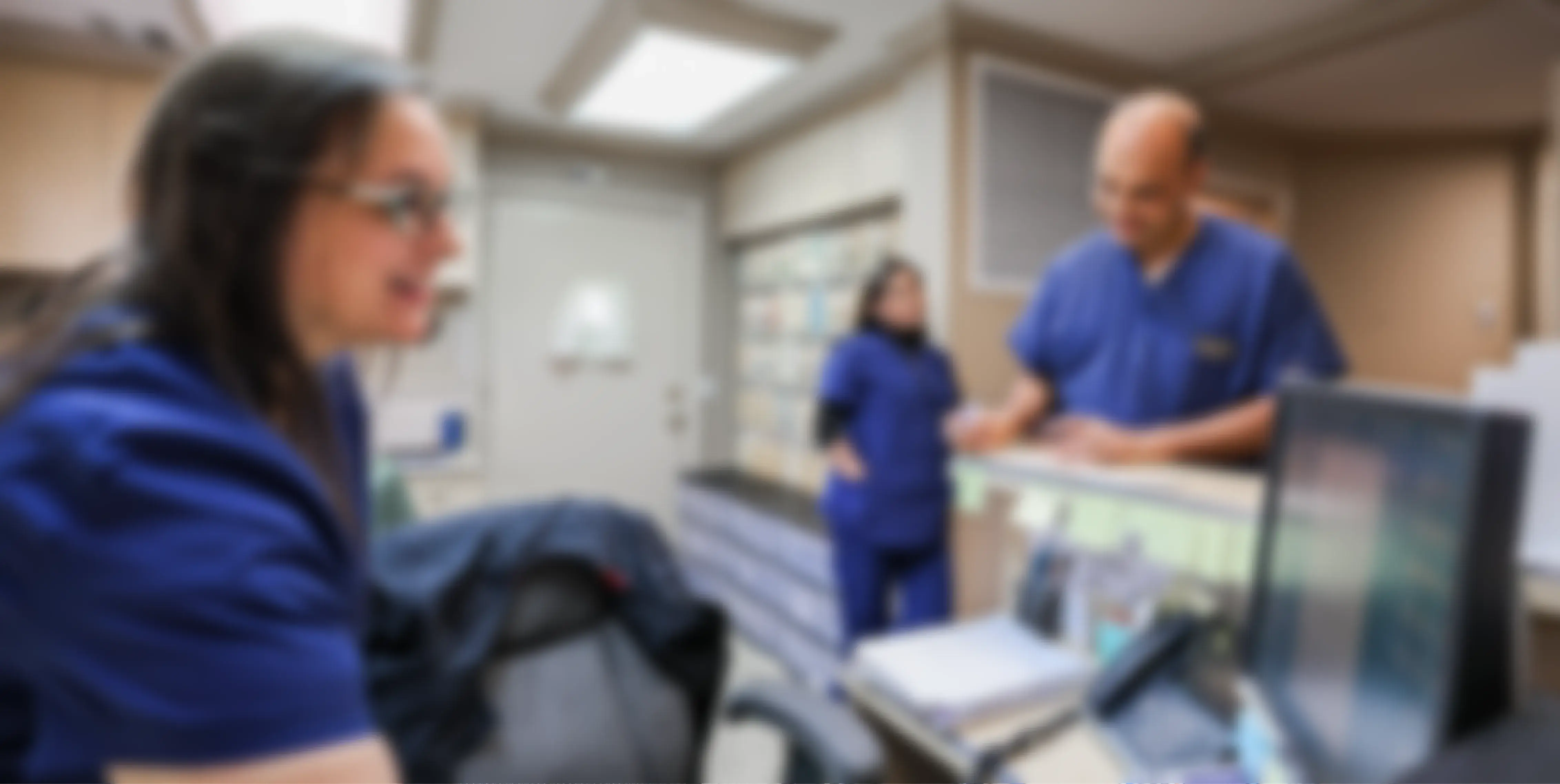 A man and a woman in scrubs looking at a computer screen.