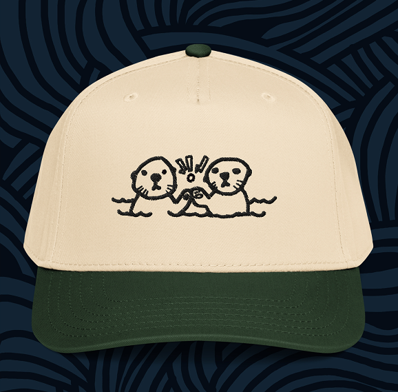 A cute hat for Monterey Surf School that has two otters dapping each other up and mad dogging the viewer